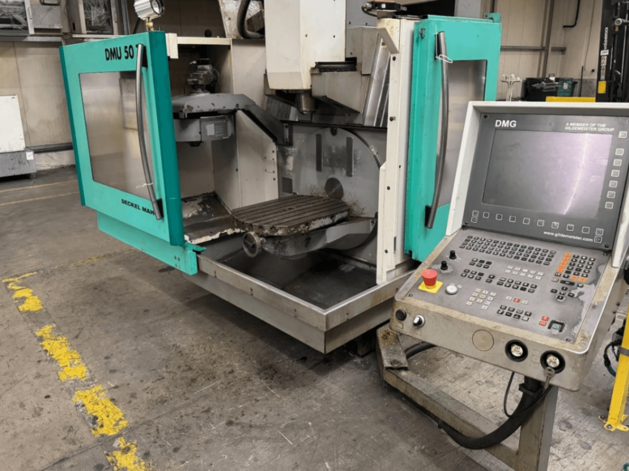 DMG DMU 50 freze makinesi, önden bakıldığında iç kısmı ve kontrol panelini gösteren açık kapılar ile.