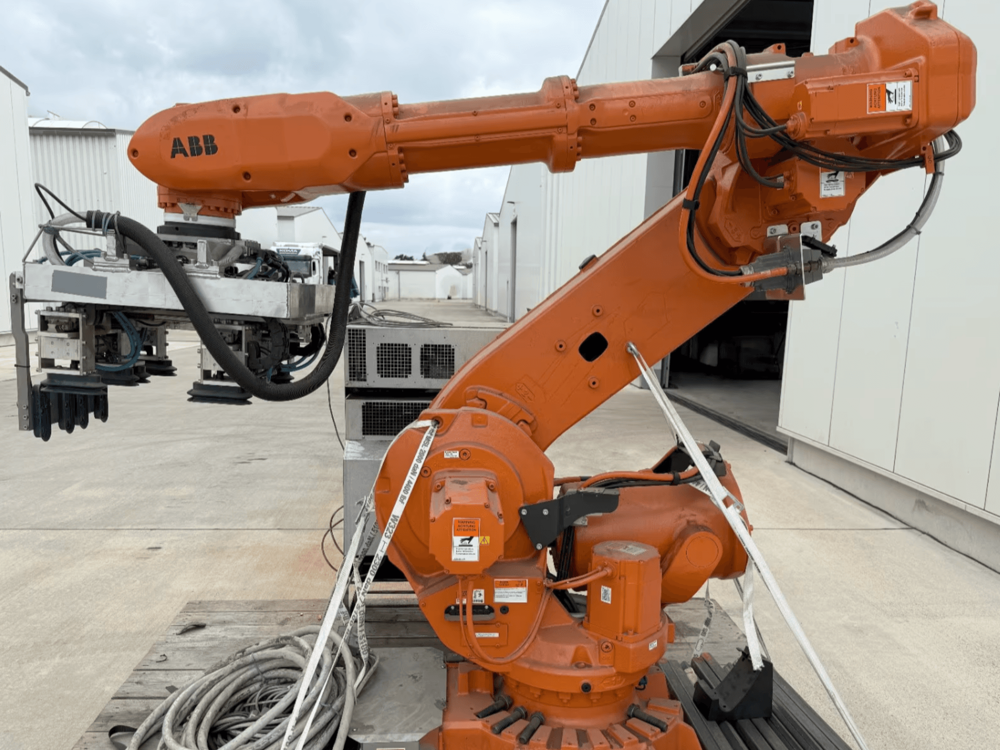 ABB RB 6600-130/3.2 robot kolunun yandan görünümü, kavrayıcı ataşmanı ve görünür kabloları olan turuncu bir robot koluna sahiptir.