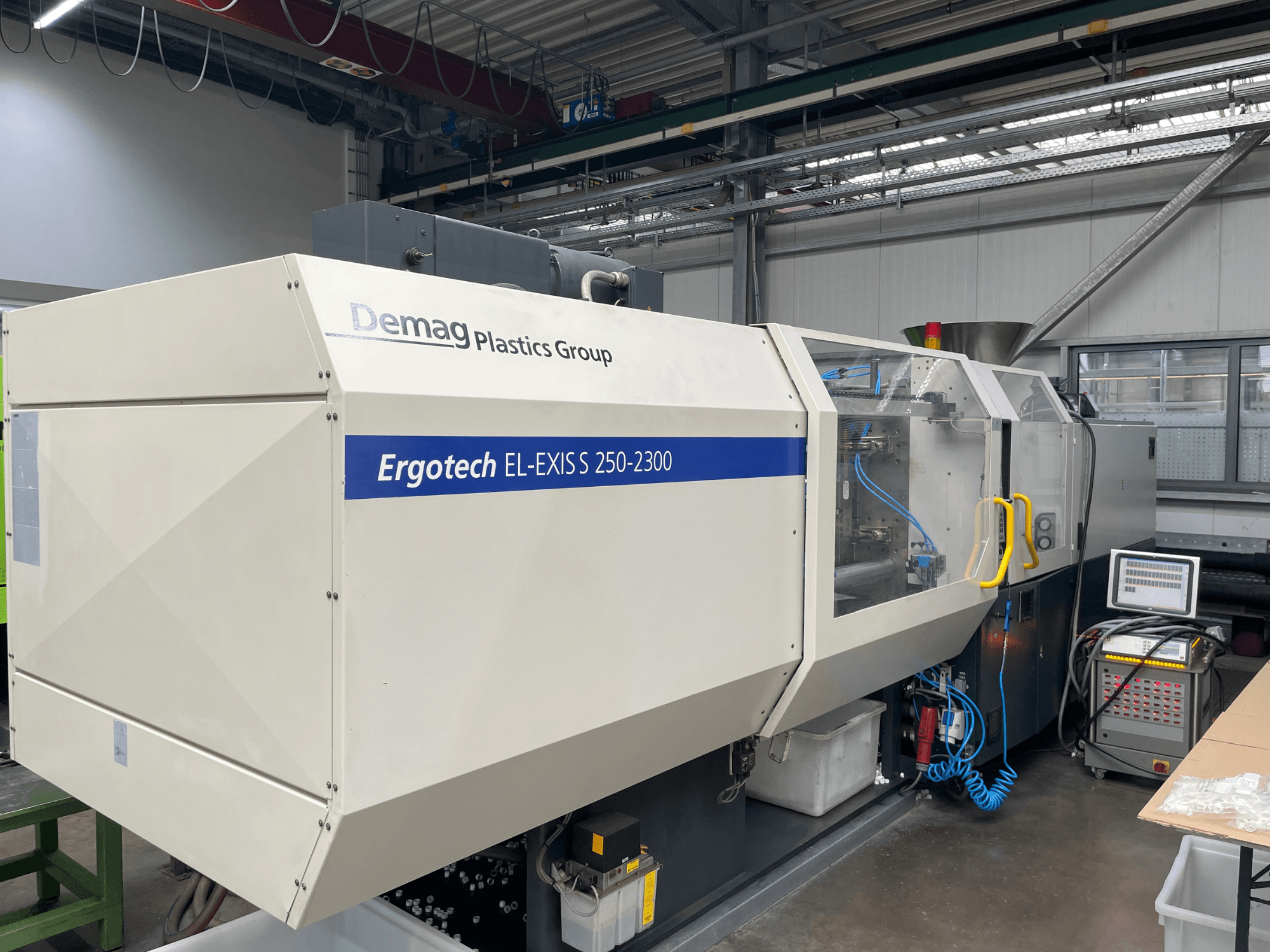 Demag Ergotech EL-EXIS S 250-2300 enjeksiyon kalıplama makinesi, yandan görünüm, kontrol paneli ve besleme sistemi.