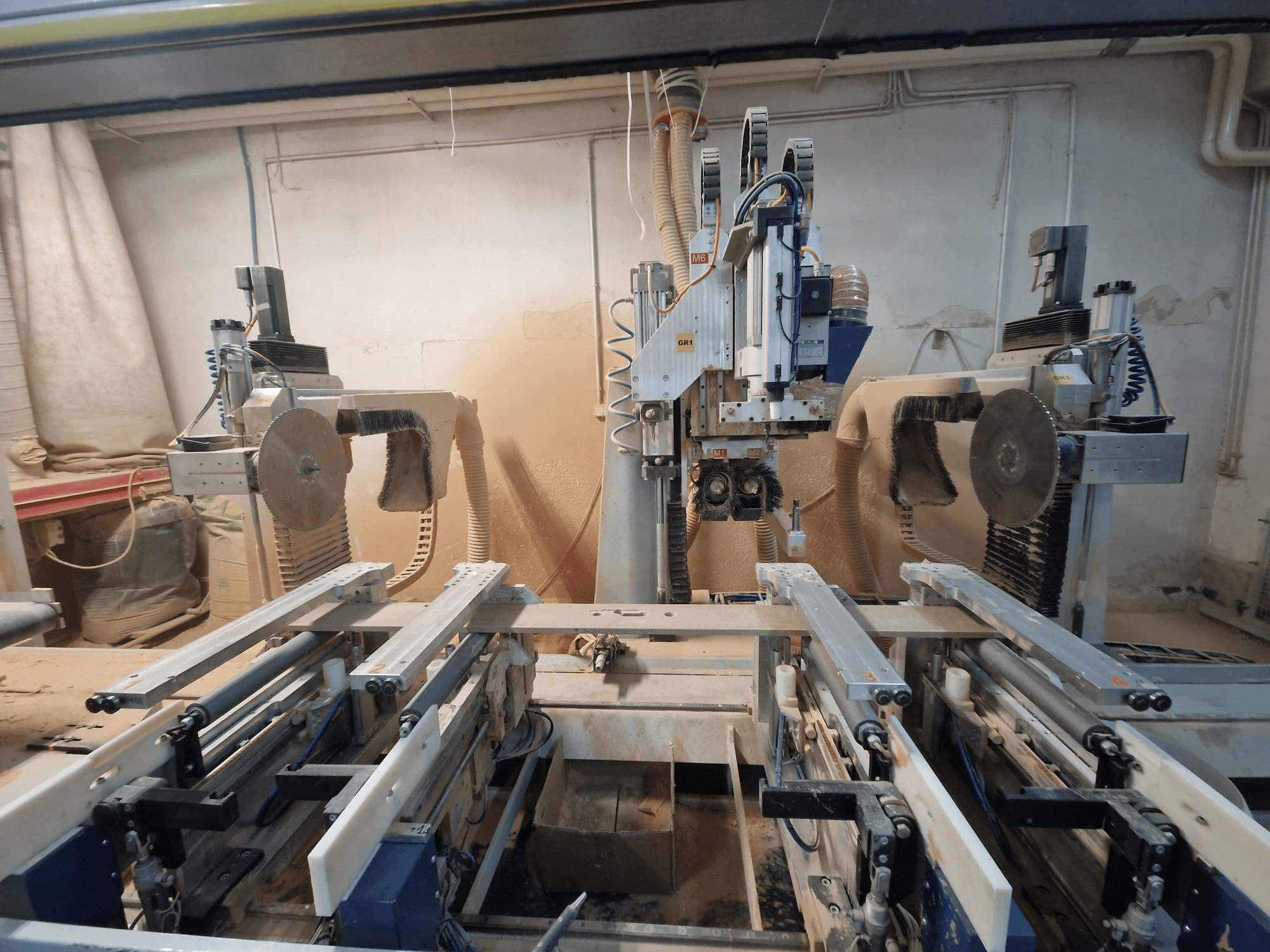 Çift testere bıçaklı ve raylı CNC makinesi, önden görünüm. Ahşap işleme için uygun toz emme sistemleri görülebilir.