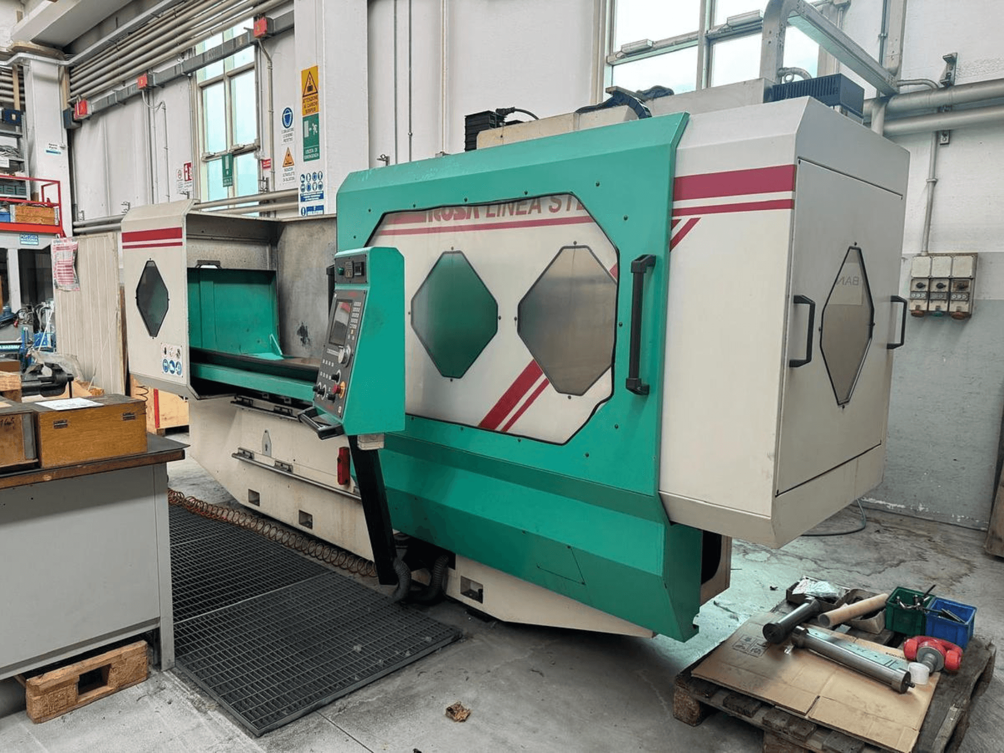 Yeşil ve beyaz hassas makine, önden görünüm, kontrol paneli, çalışma alanı ve bir palet üzerinde aletler. Marka: BAMB.