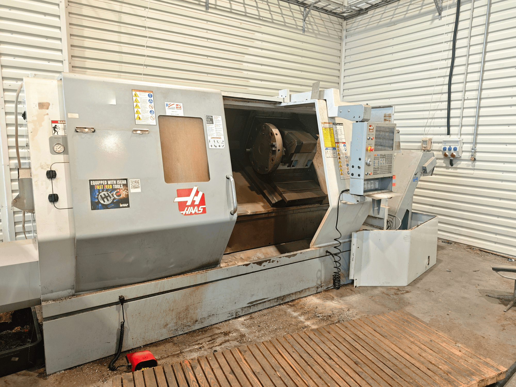 Haas SL-40HE yatay torna tezgahı, önden görünüm; kontrol paneli, çalışma alanı ve güvenlik etiketleri gösterilmektedir.