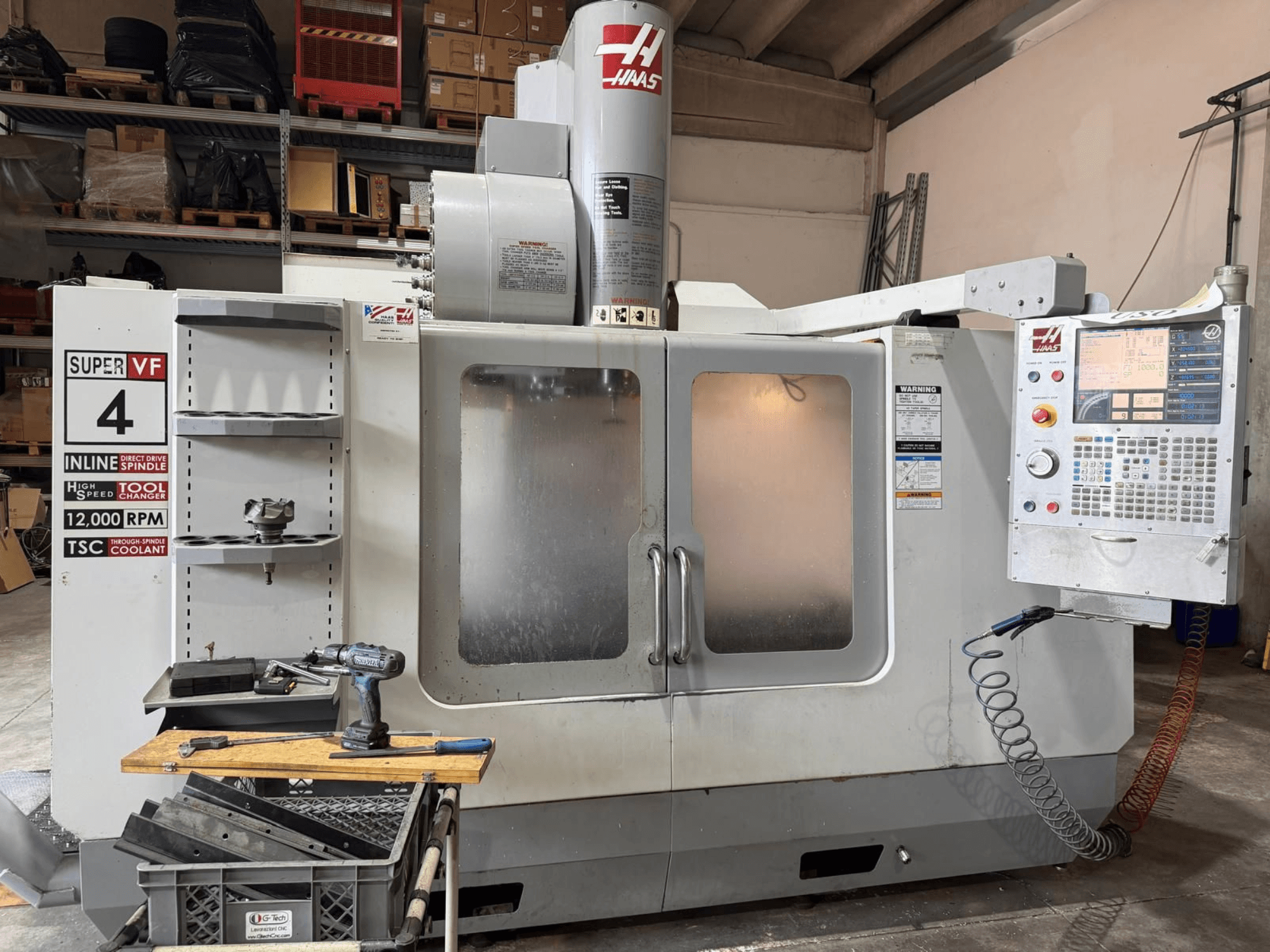 Kontrol paneli, takım rafı ve 12.000 dev/dak hızında iş mili bulunan HAAS VF-4SSHE dikey işleme merkezinin önden görünümü; yüksek hızlı, hassas bir makine.