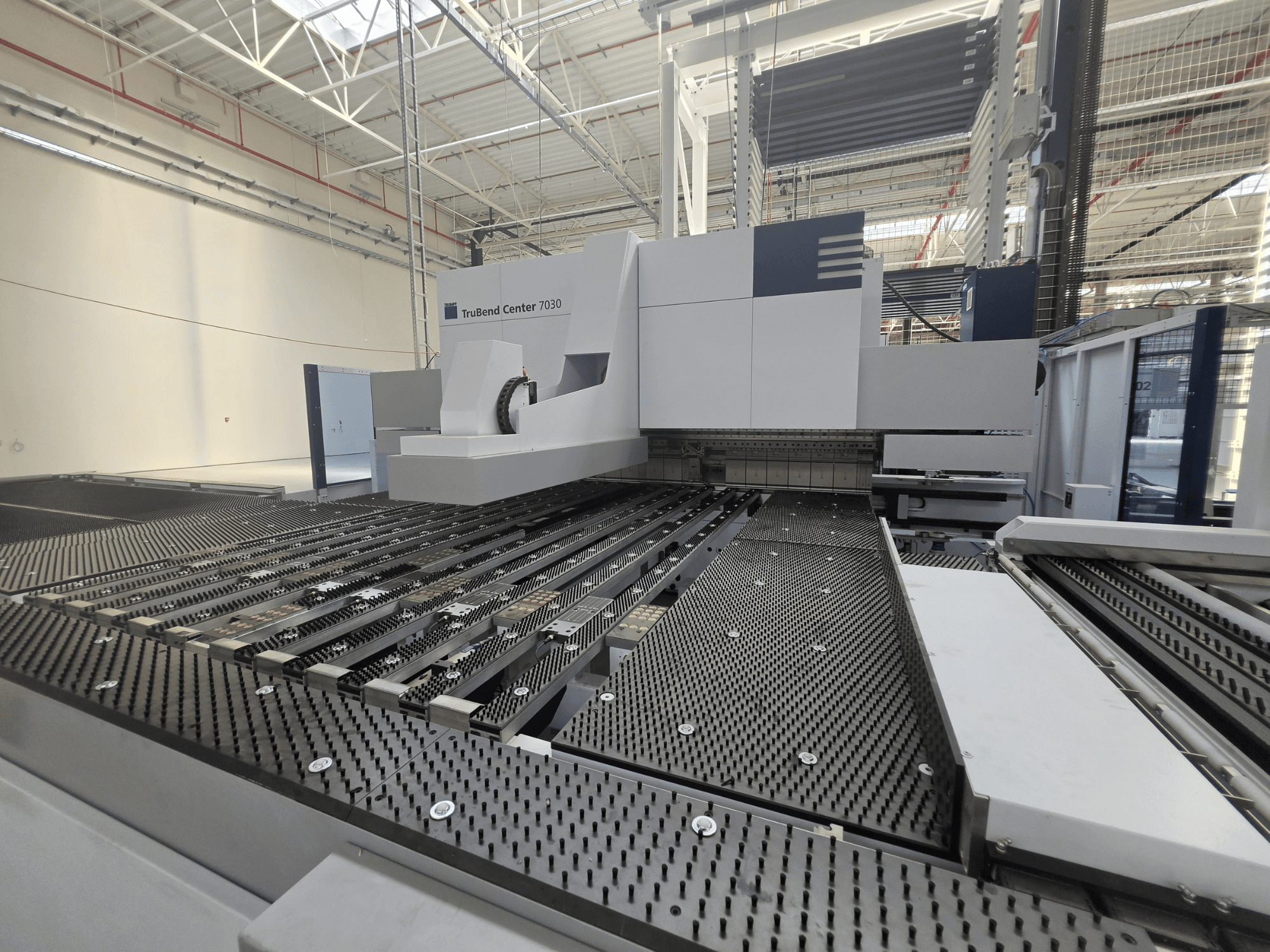 Fabrika ortamında bulunan TRUMPF TruBend Center 7030 bükme makinesi; karmaşık yapıdaki çalışma masası ve bükme kolunu gösteren önden görünüm.