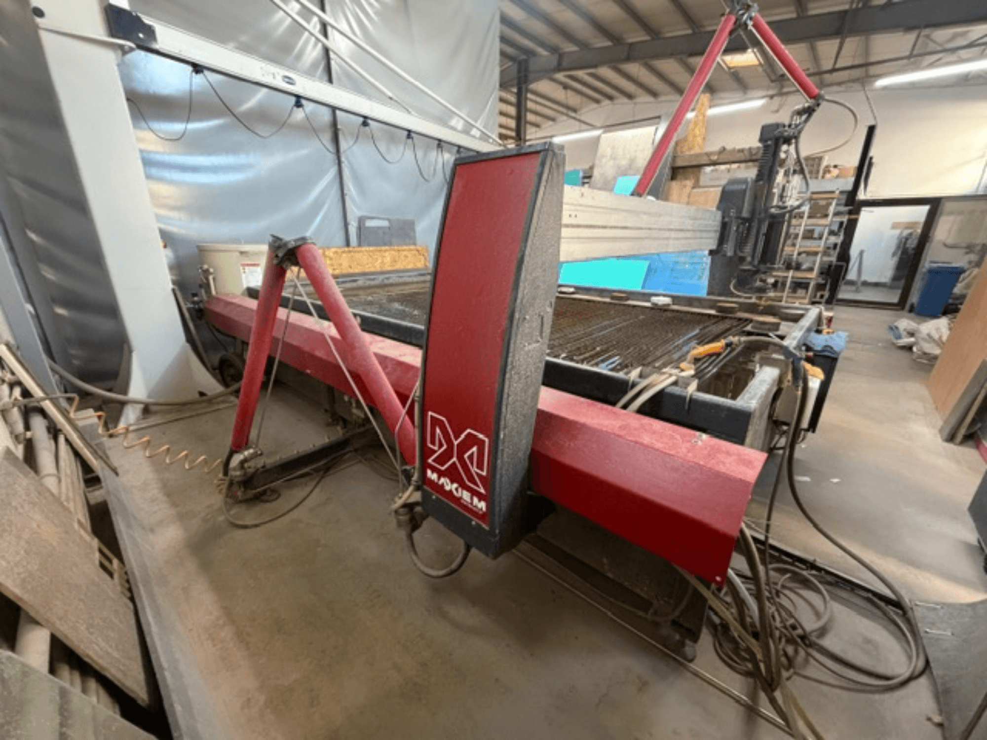 X markalı kırmızı su jeti kesim makinesi, yandan bakıldığında mekanik bileşenleri ve boru detaylarını gösteriyor.