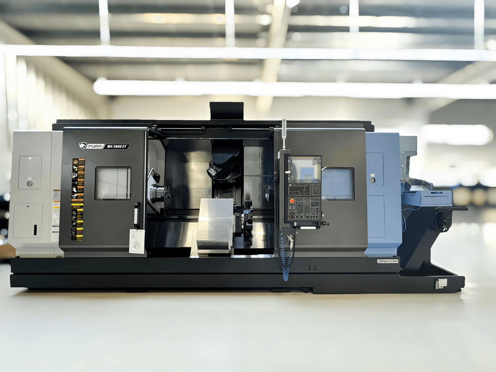 Puma MX2600ST Freze-Torna Merkezi yandan görünümde, ayrıntılı kontrol paneli ve görünür takımlarla işleme alanı.