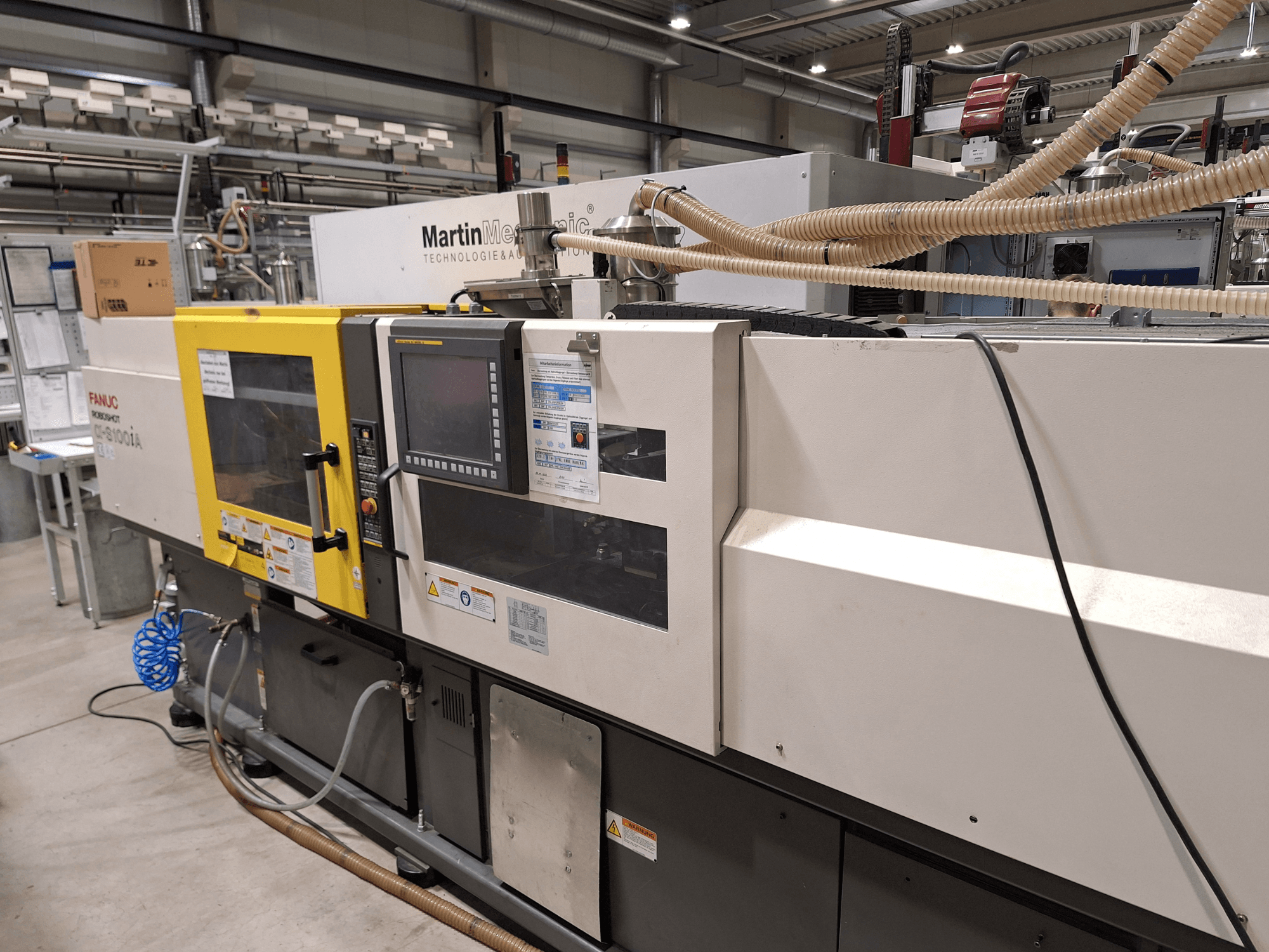 FANUC Roboshot S100iA elektrikli enjeksiyon kalıplama makinesi, yandan görünüm, dokunmatik ekran ve güvenlik etiketleri ile donatılmıştır.