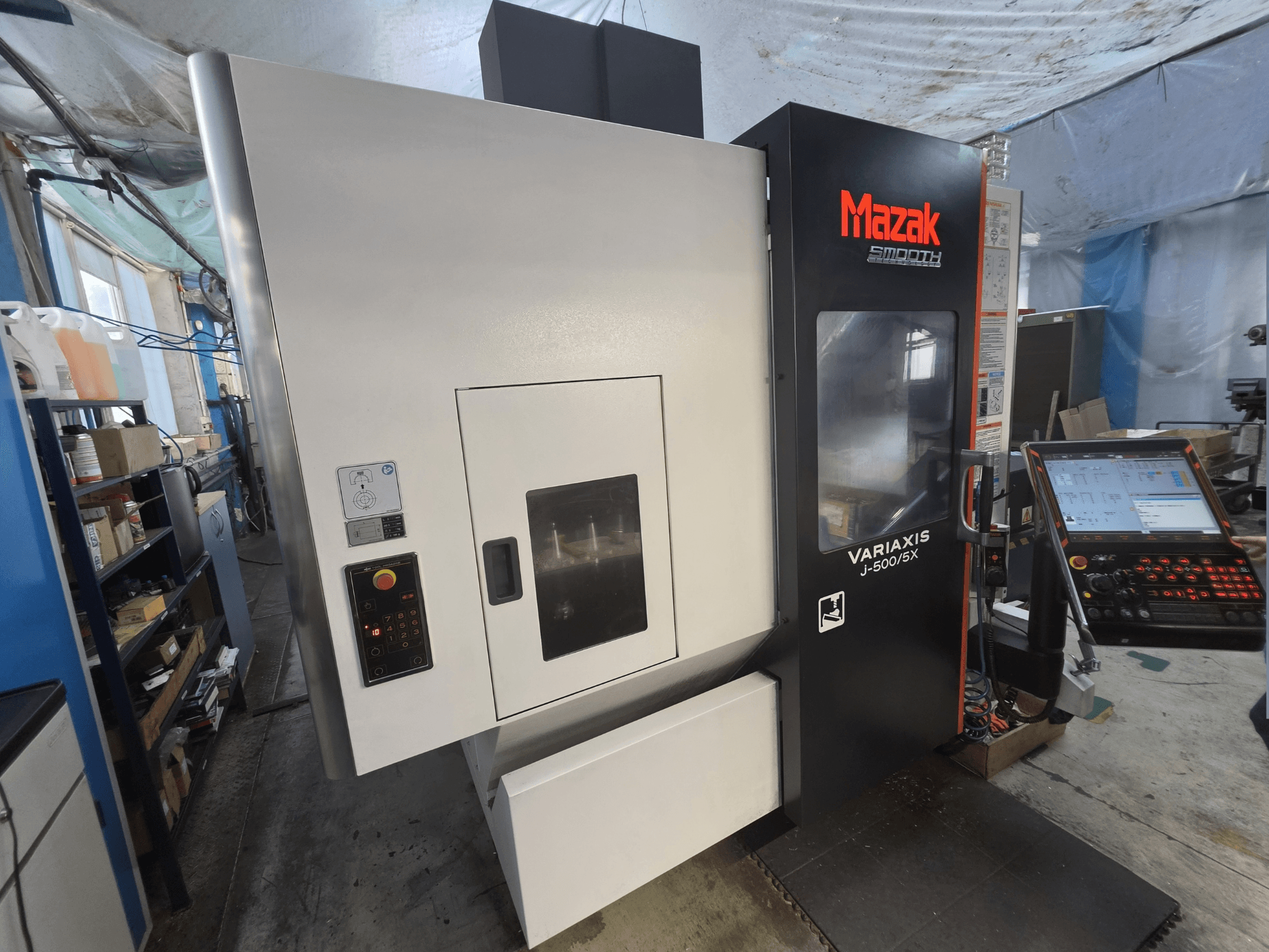 Önden görünüşte, kontrol paneli ve geniş işleme bölmesi penceresi bulunan Mazak VARIAXIS J-500/5X dikey işleme merkezi.