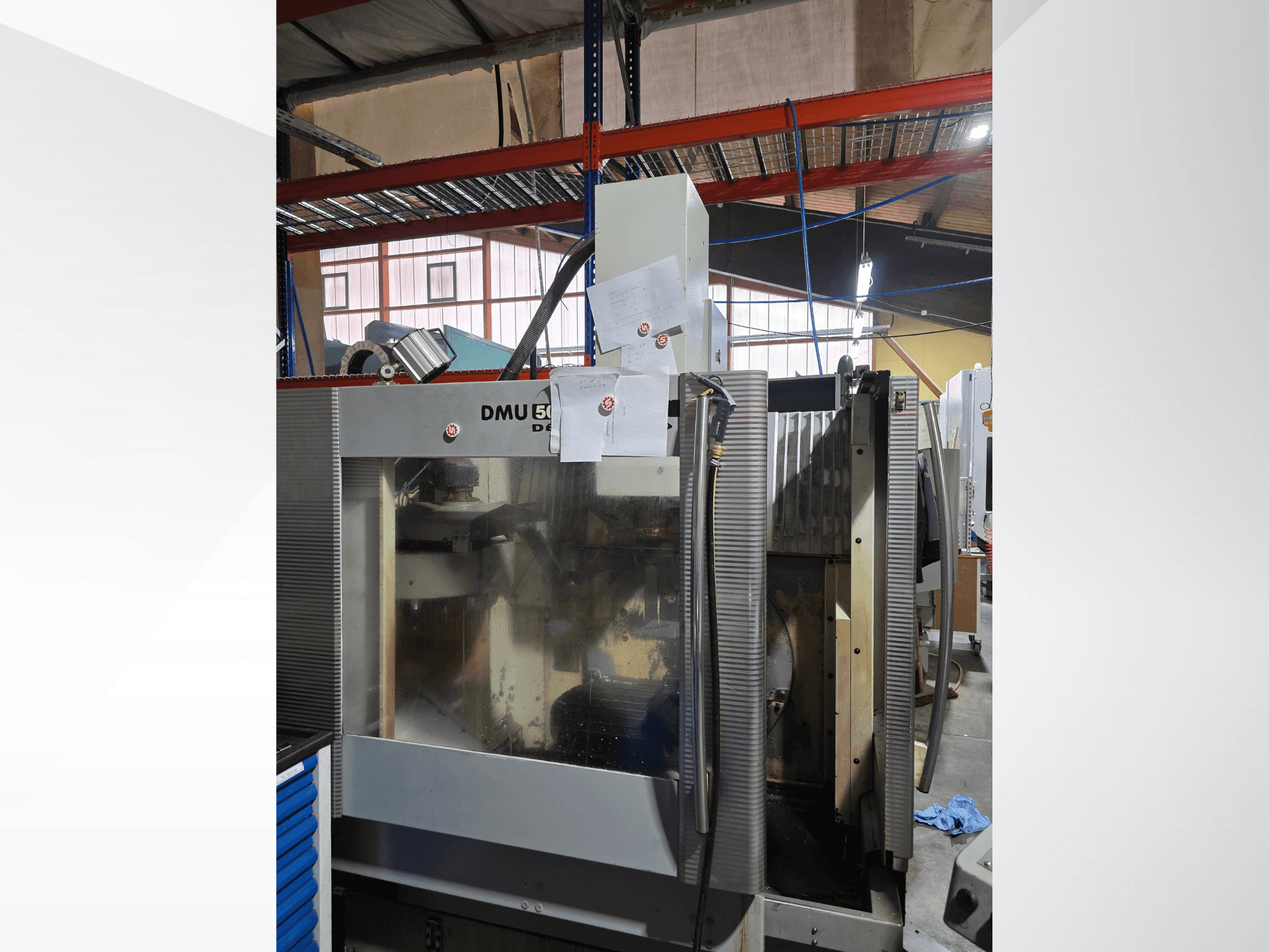 DMU 50 3 eksenli CNC işleme merkezi bir atölyede, önden gösterilmiş, operasyonel bileşenleri ve ekli belgeleri gösteriyor.