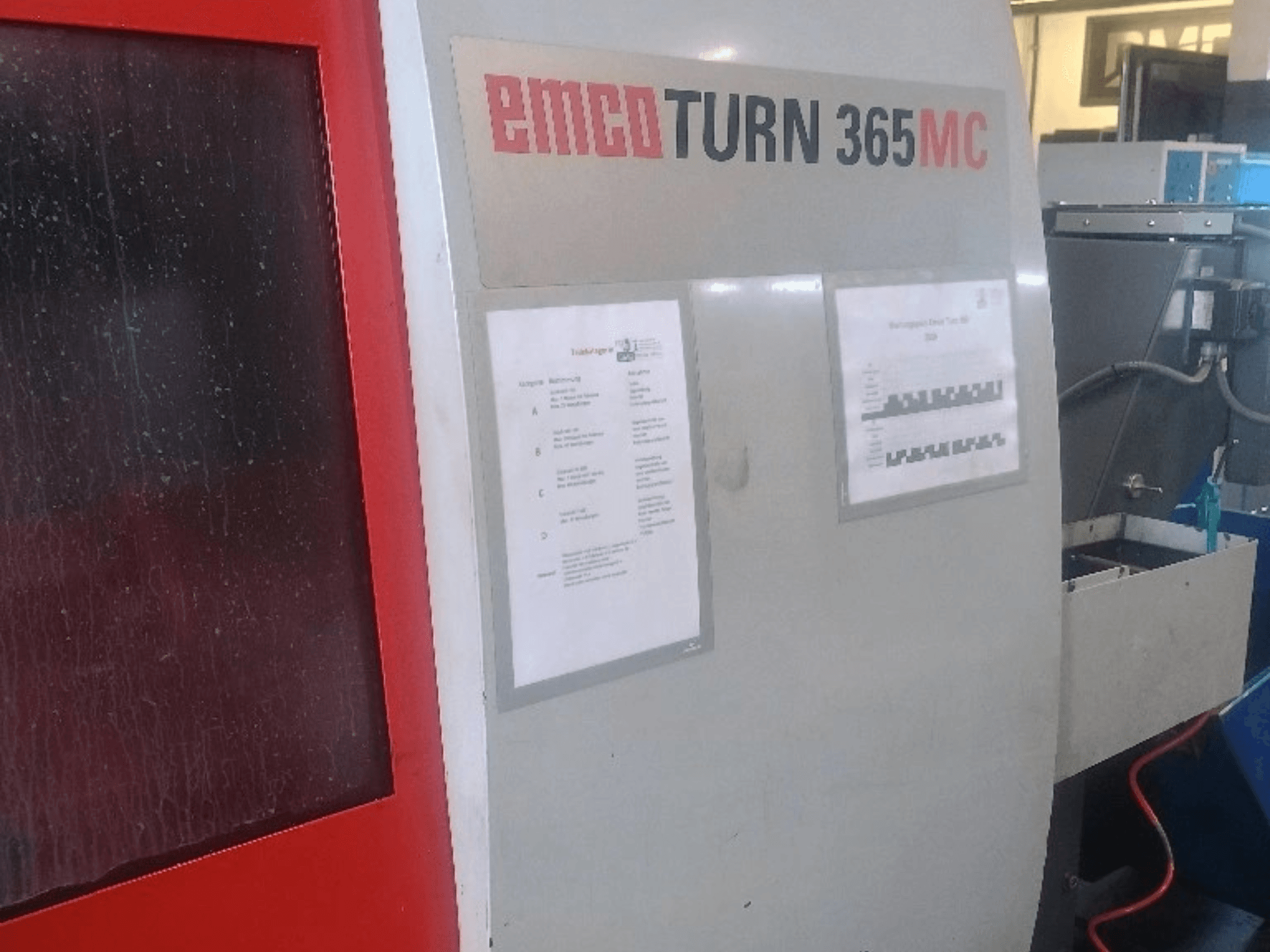 EMCO EmcoTurn 365 MC yatay torna tezgahı; kontrol paneli, kullanım kılavuzları ve mavi soğutma sıvısı tankının görüldüğü yandan görünüm.