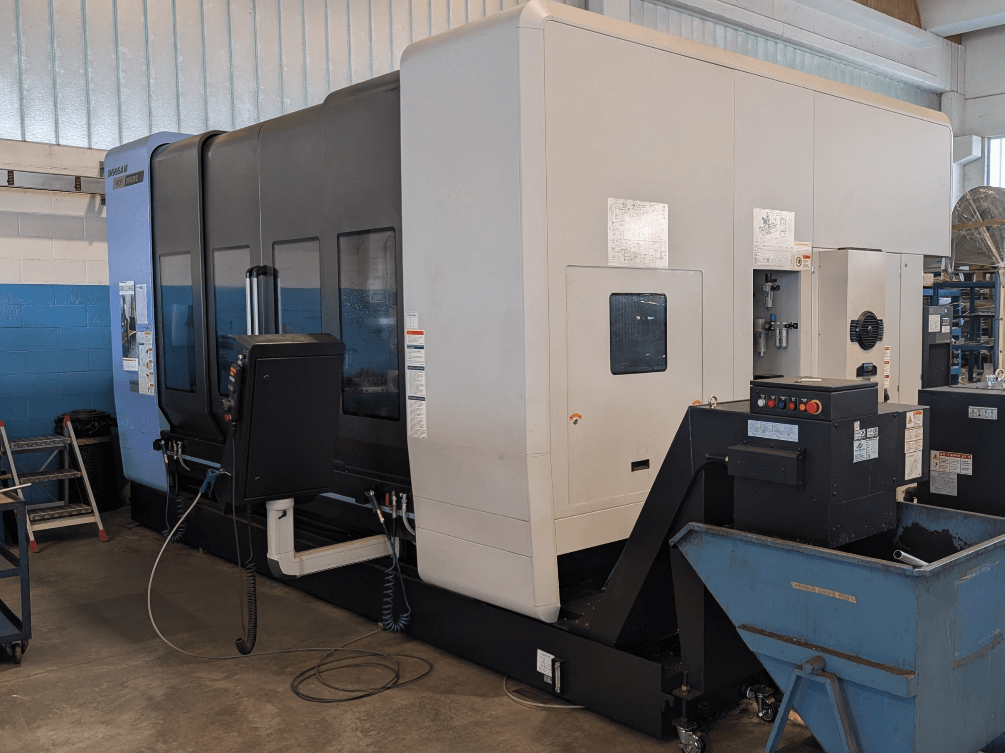 DOOSAN VCF850LSR-II dikey işleme merkezinin yandan görünümü; kontrol paneli, soğutma sıvısı sistemi ve sağlam yapısı göze çarpmaktadır.