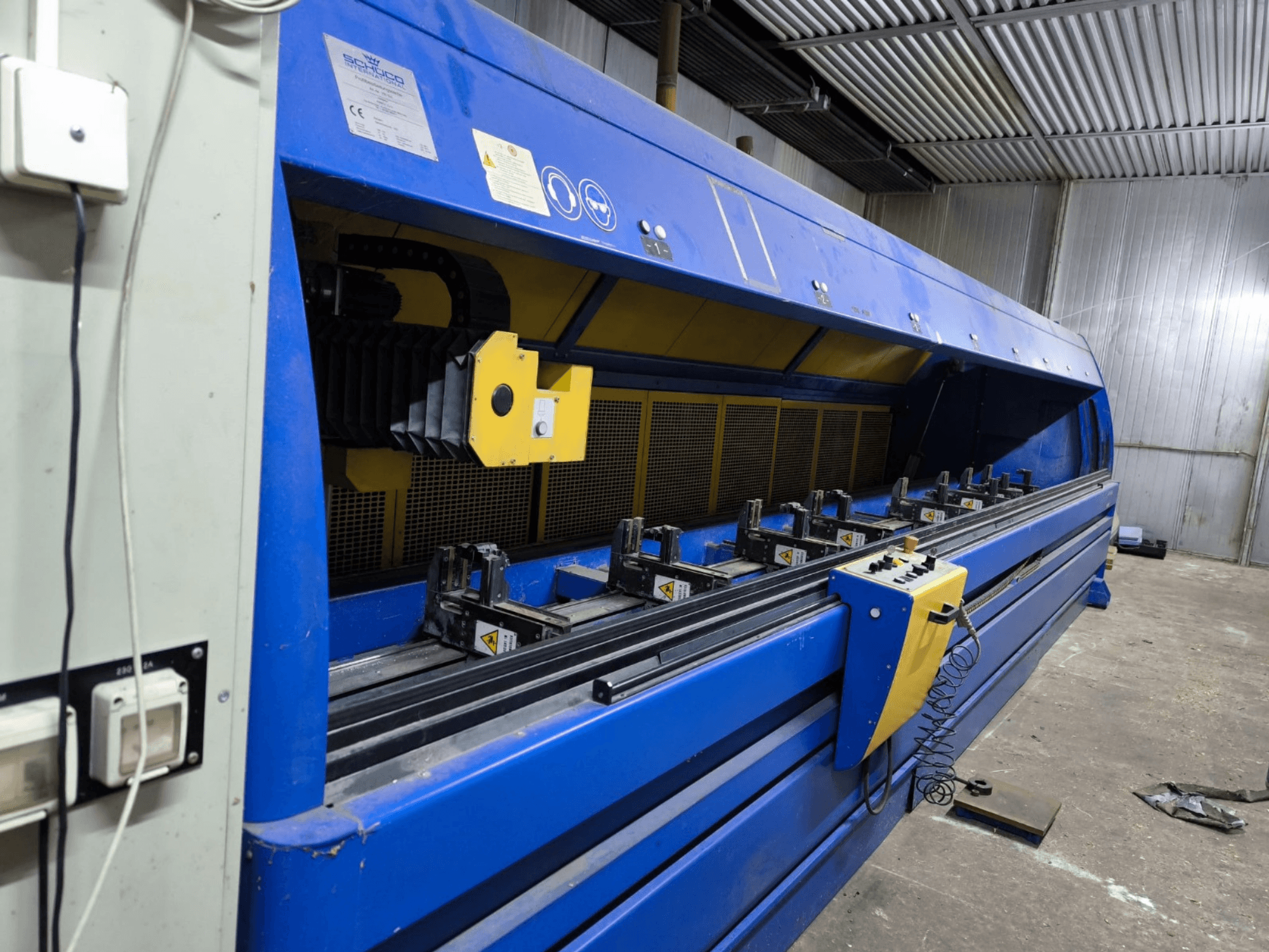 Mavi renkli Schneider endüstriyel kesim makinesi, yandan görünüm, kontrol paneli, kayışlar ve çoklu sıkıştırma istasyonları görülebilir.