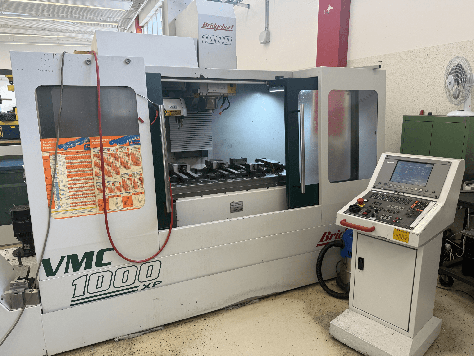 Bridgeport VMC 1000 XP dikey işleme merkezinin önden görünümü; bu görünümde kontrol paneli, çalışma alanı ve takım yuvaları gösterilmektedir.