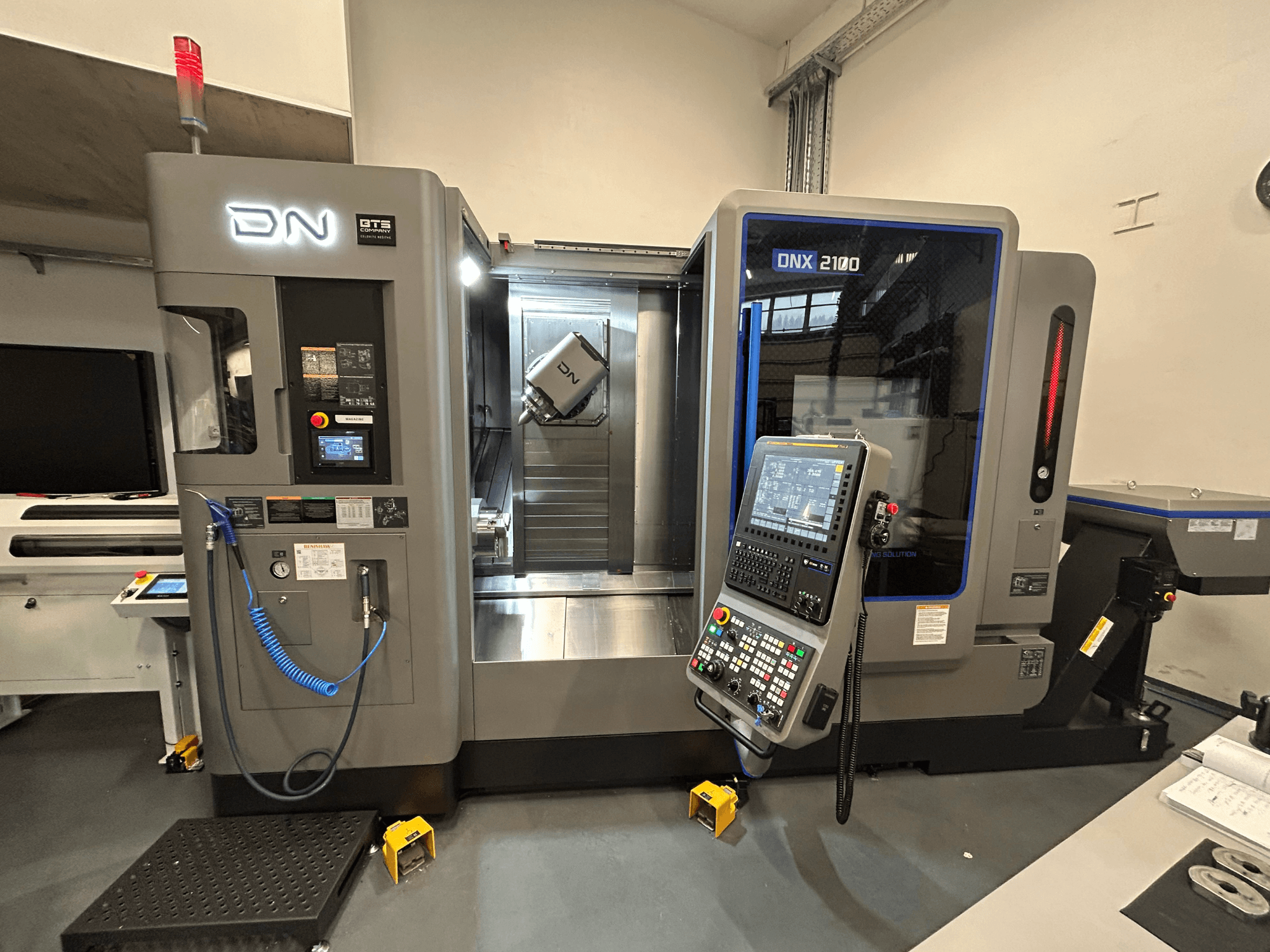 DN ONX 2100 CNC makinesi, önden görünüm, kontrol paneli, çalışma alanı ve takım özellikleri. Güvenlik ışığı ve çalışma göstergeleri ile donatılmıştır.