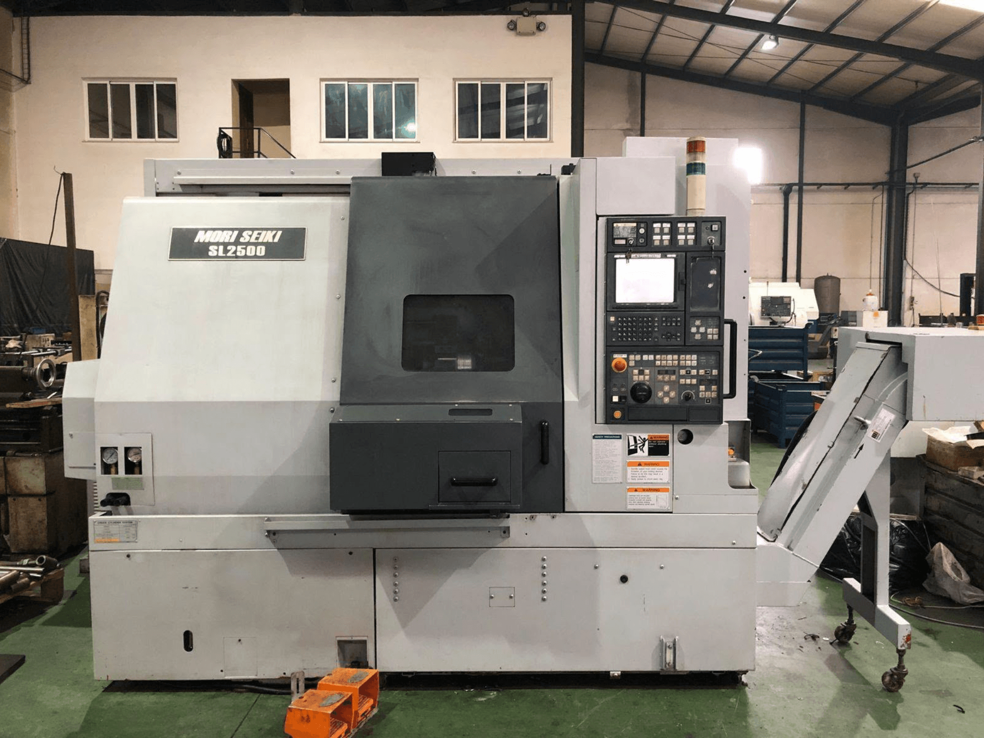 DMG Mori Seiki SL 2500 Y torna-freze merkezi; kontrol paneli ve talaş konveyörü görülebilen yandan görünüm.