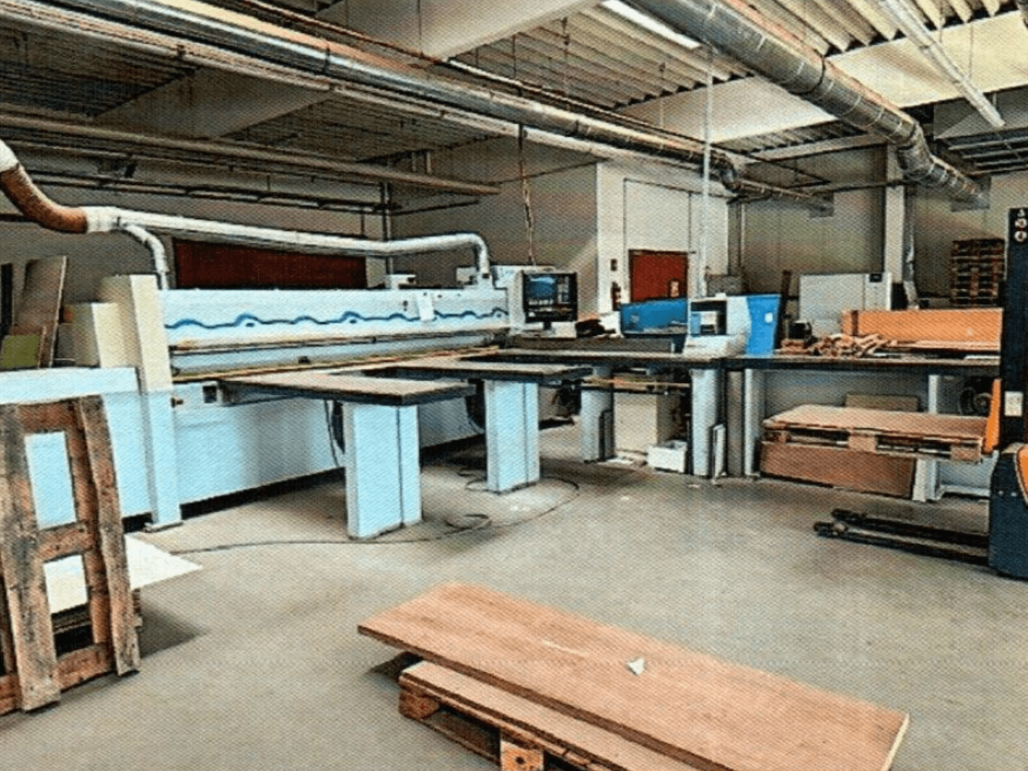 HOMAG HPL 11/38/22 panel testeresi, büyük bir kesim masası ve teşhir konsoluna sahip bir atölyede, önden görünüm.