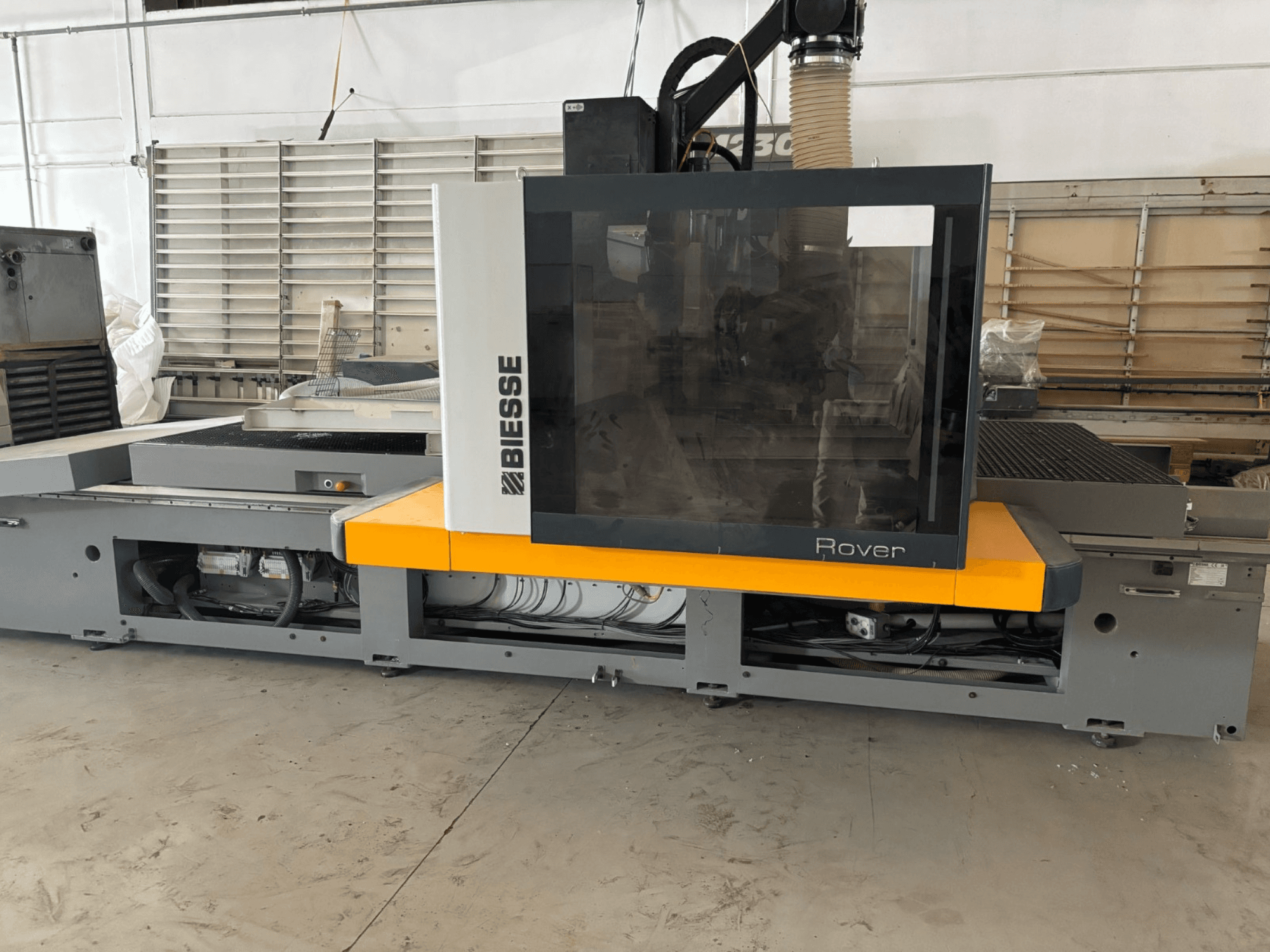 Biesse Rover CNC işleme merkezi, önden görünüm, büyük bir kontrol paneli, sarı vurgular ve açık mekanik bileşenlere sahiptir.