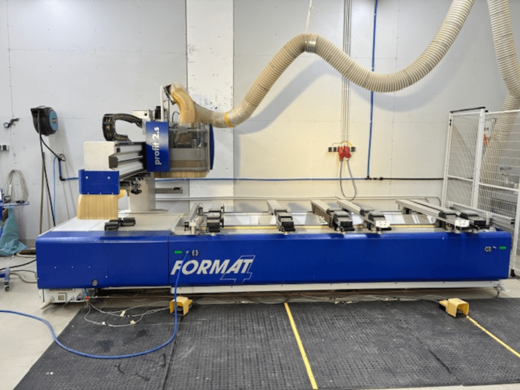Mavi FORMAT 4 CNC router, model Profit 2.5, kesim alanını ve toz emme sistemini gösteren yandan görünüm, kauçuk bir mat üzerinde.