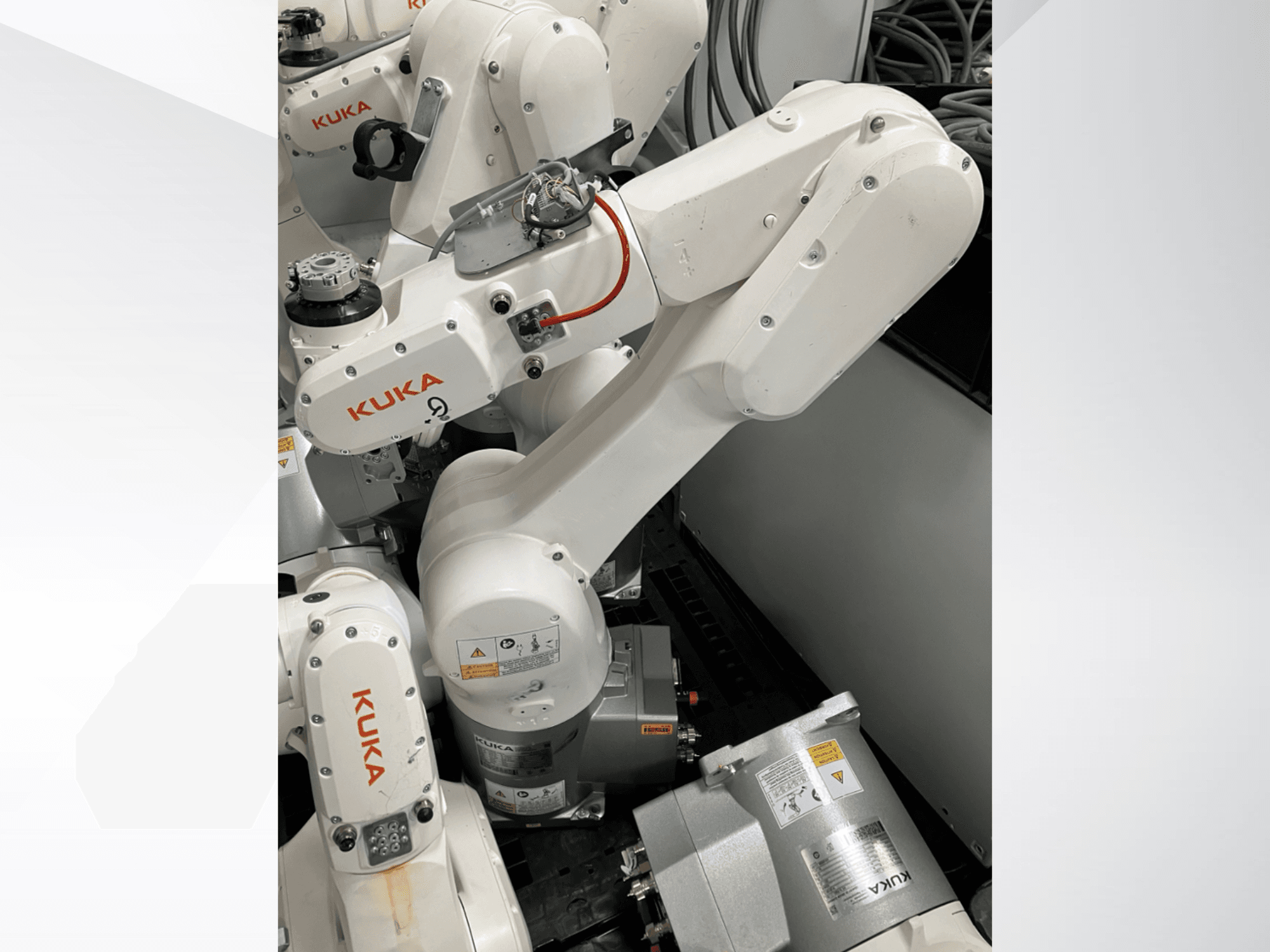 KUKA KR 6 R900 CR robot kolu, yandan görünüm; görünür motorlar ve konektörler, etiketli güvenlik uyarıları ve mekanik kollara sahiptir.