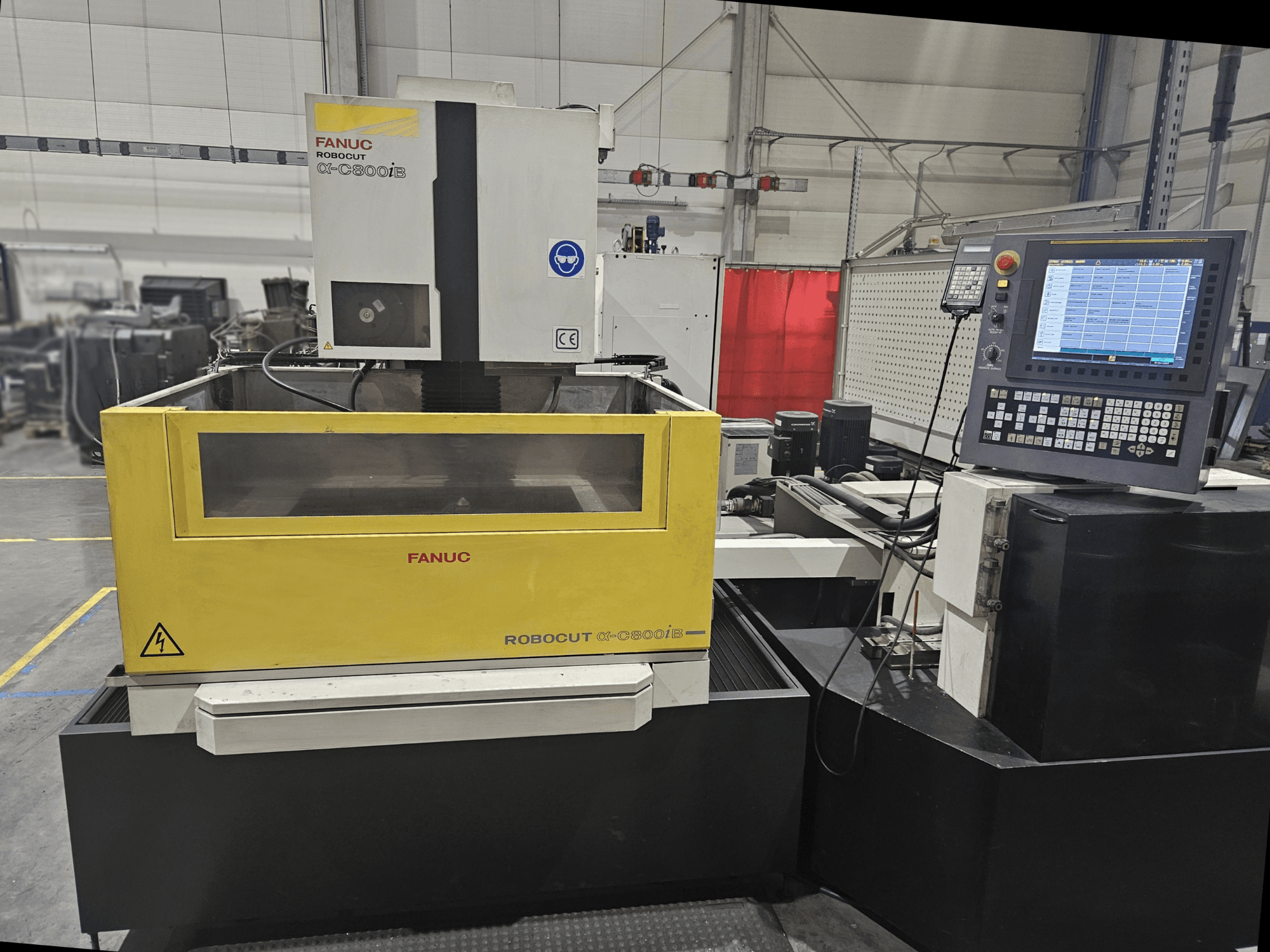 Sarı ve gri makine gövdesi, CNC kontrol paneli ve çalışma ekranı ile FANUC Robocut α-C600iB'nin önden görünümü.