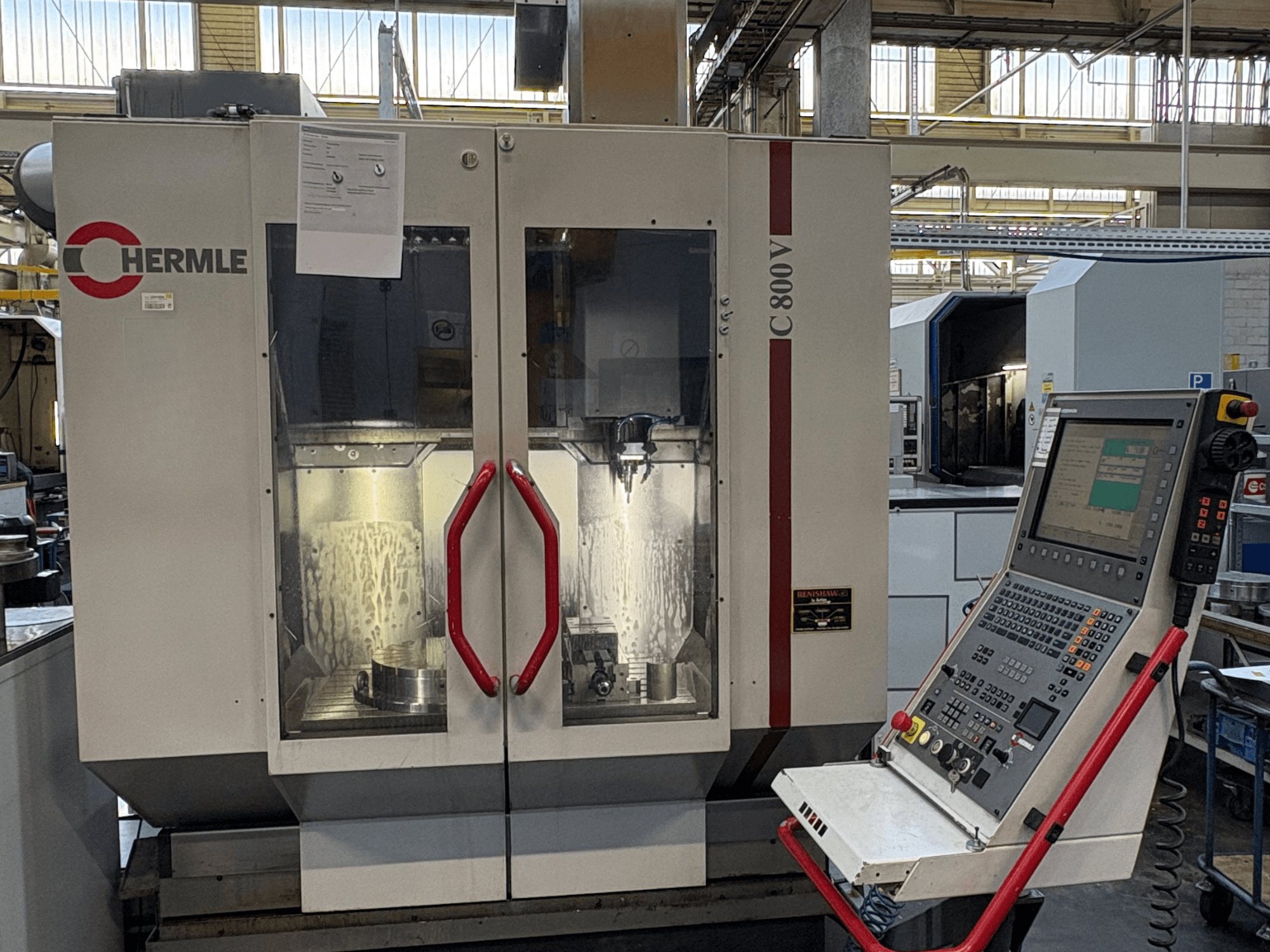 HERMLE C 800 V dikey işleme merkezi, önden görünüm; kırmızı kulplu kapaklar ve sağ tarafta kontrol paneli.