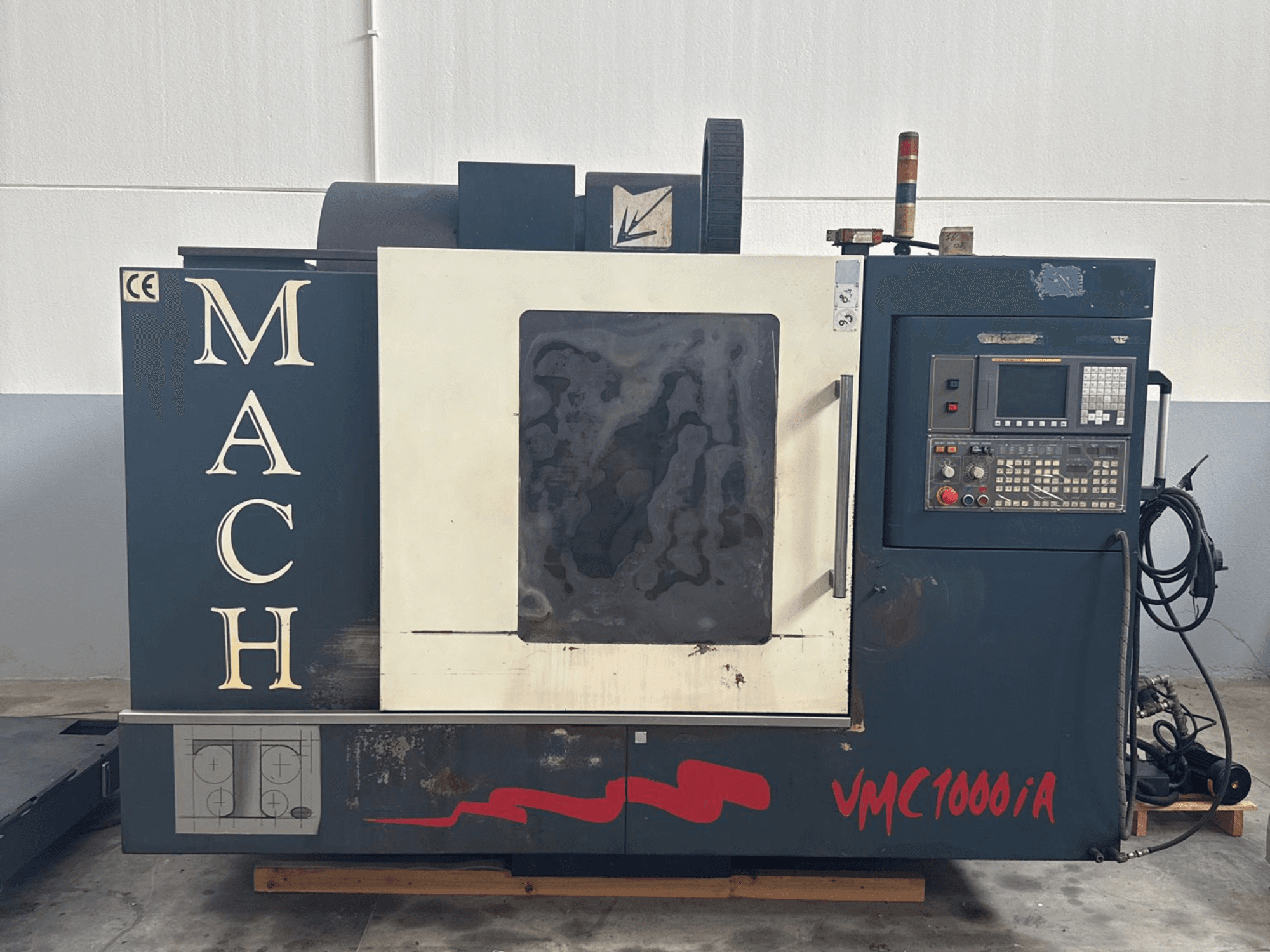 Dikey işleme merkezi MIND MACH VMC 1000/A'nın önden görünümü, kontrol paneli, iş mili ve taban işaretleri.