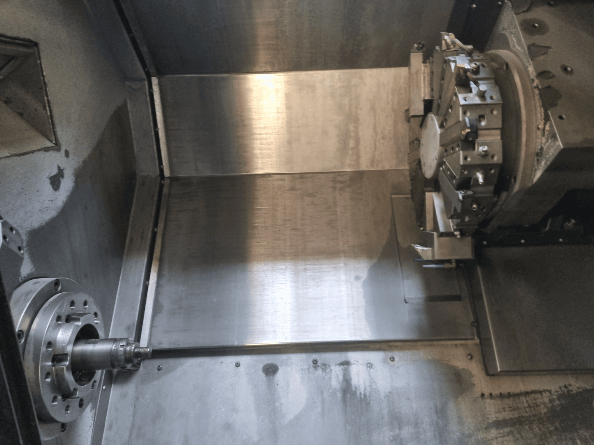 Dönen bir iş mili ve metal çalışma yüzeyine sahip, endüstriyel hassas mühendisliği sergileyen bir CNC torna tezgahının iç görünümü.