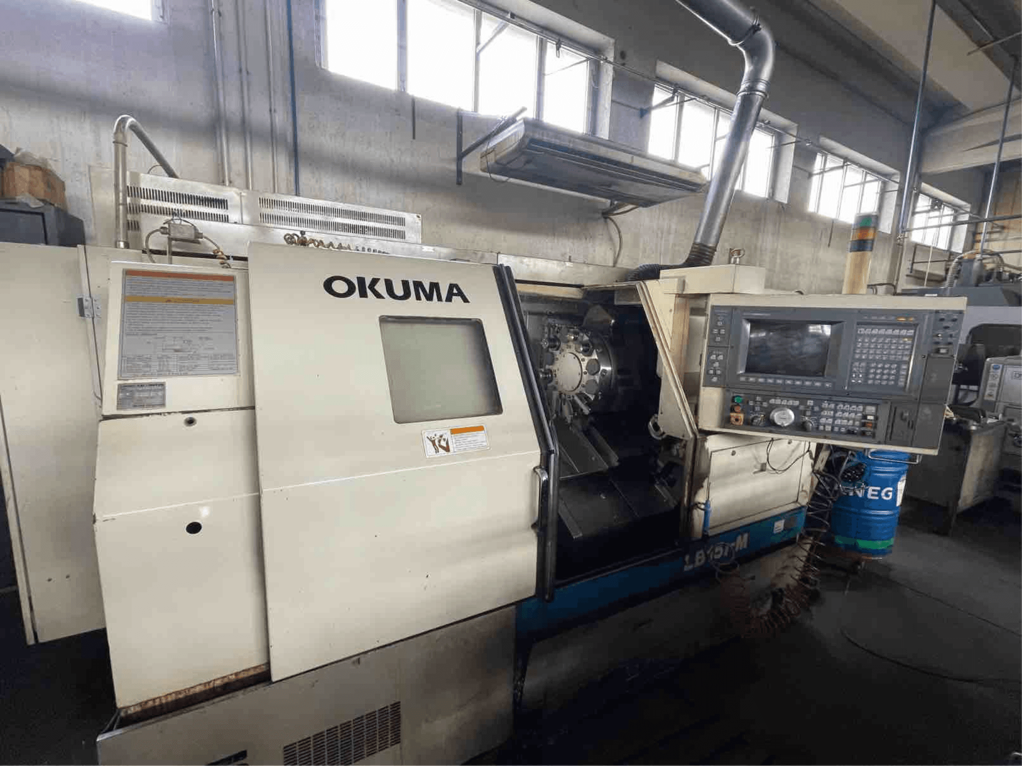 Okuma LB15i-M yatay torna makinesi, önden görünüm; kontrol paneli ve ayrıntılı göstergeli kesici takım alanı.