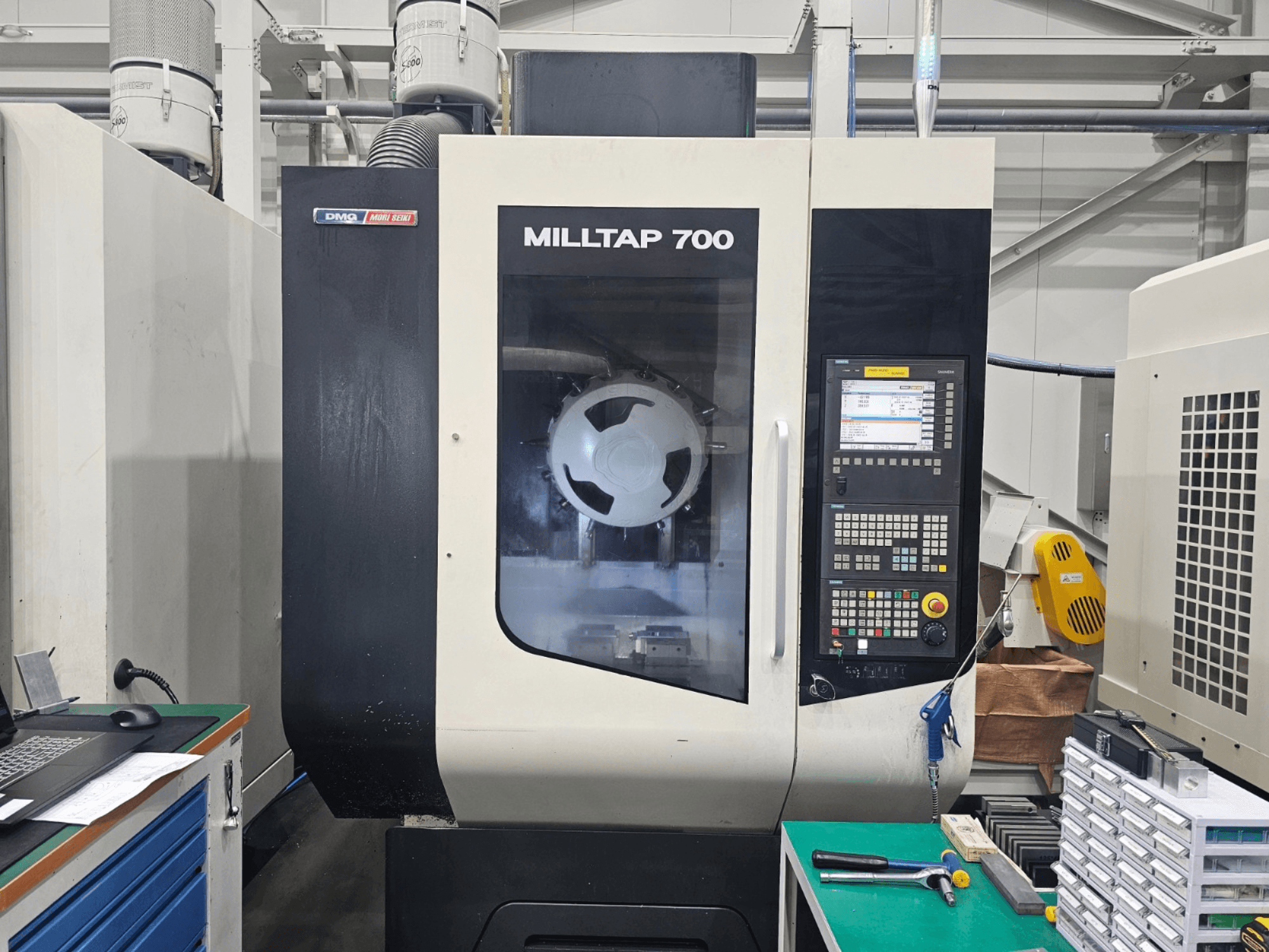 DMG MORI MILLTAP 700 dikey işleme merkezi, önden görünüm; kontrol paneli, iş mili ve çalışma alanı detaylarını göstermektedir.