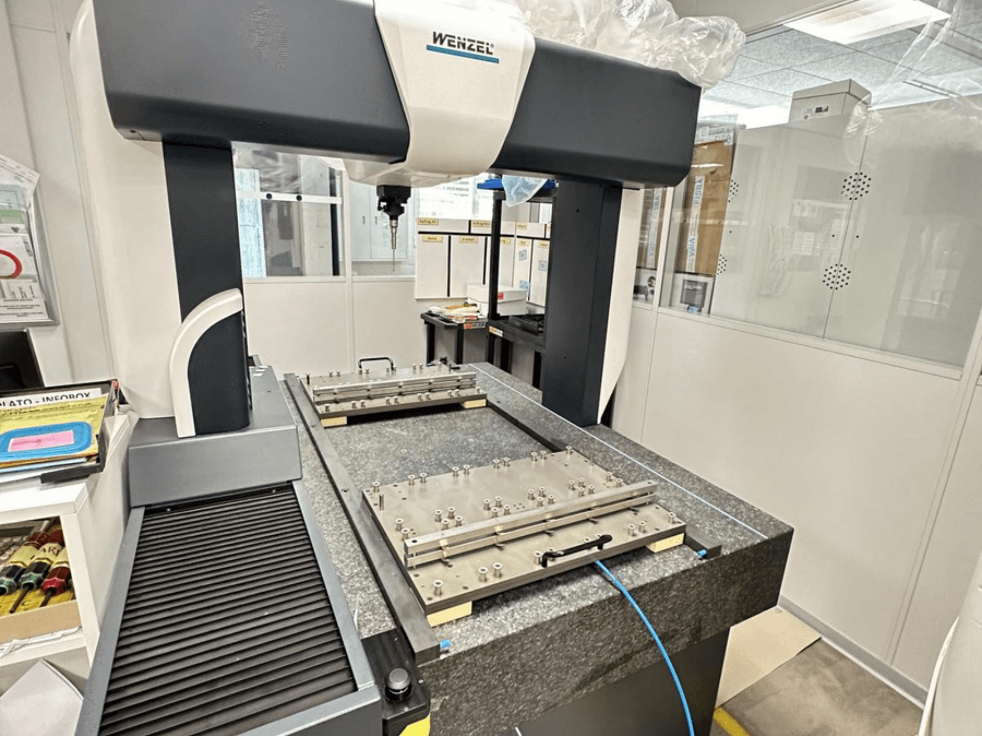 Laboratuvar ortamında bulunan Wenzel LH 65 CMM, ayarlanabilir ölçüm platformu ve üstten uzanan kolu ile granit tabanı sergiliyor.