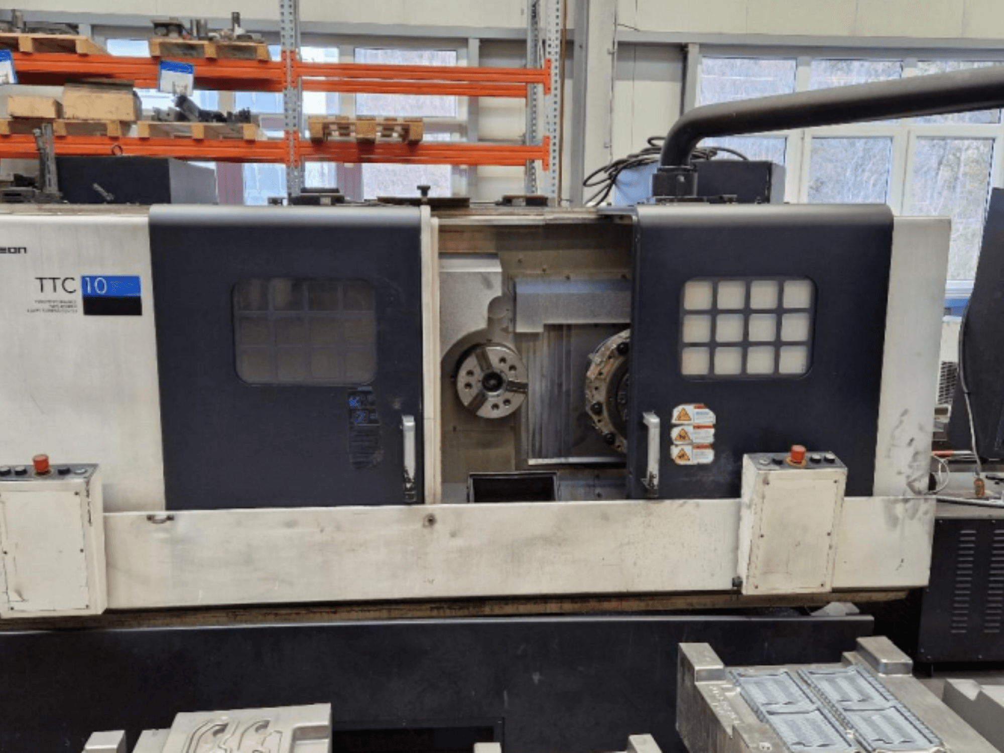 TTC 10 torna tezgahının önden görünümü, kontrol panelini, görünür aynaları ve metal parçaların bulunduğu çalışma alanını gösterir.