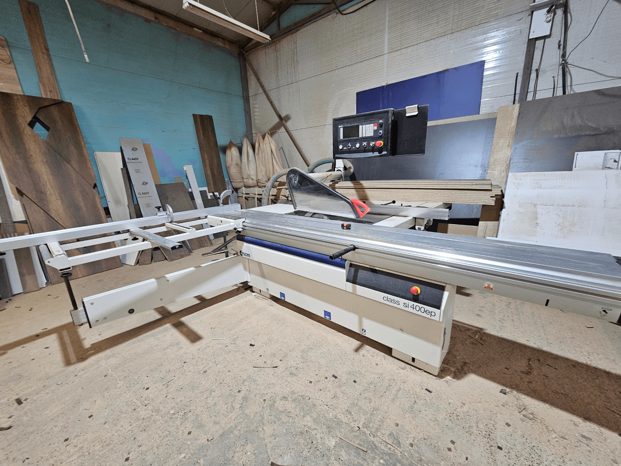 Sınıf SI400EP panel testere, önden görünüm, ayarlanabilir çitli, kumlu atölye zeminine yerleştirilmiş, ahşap panellerle çevrili.