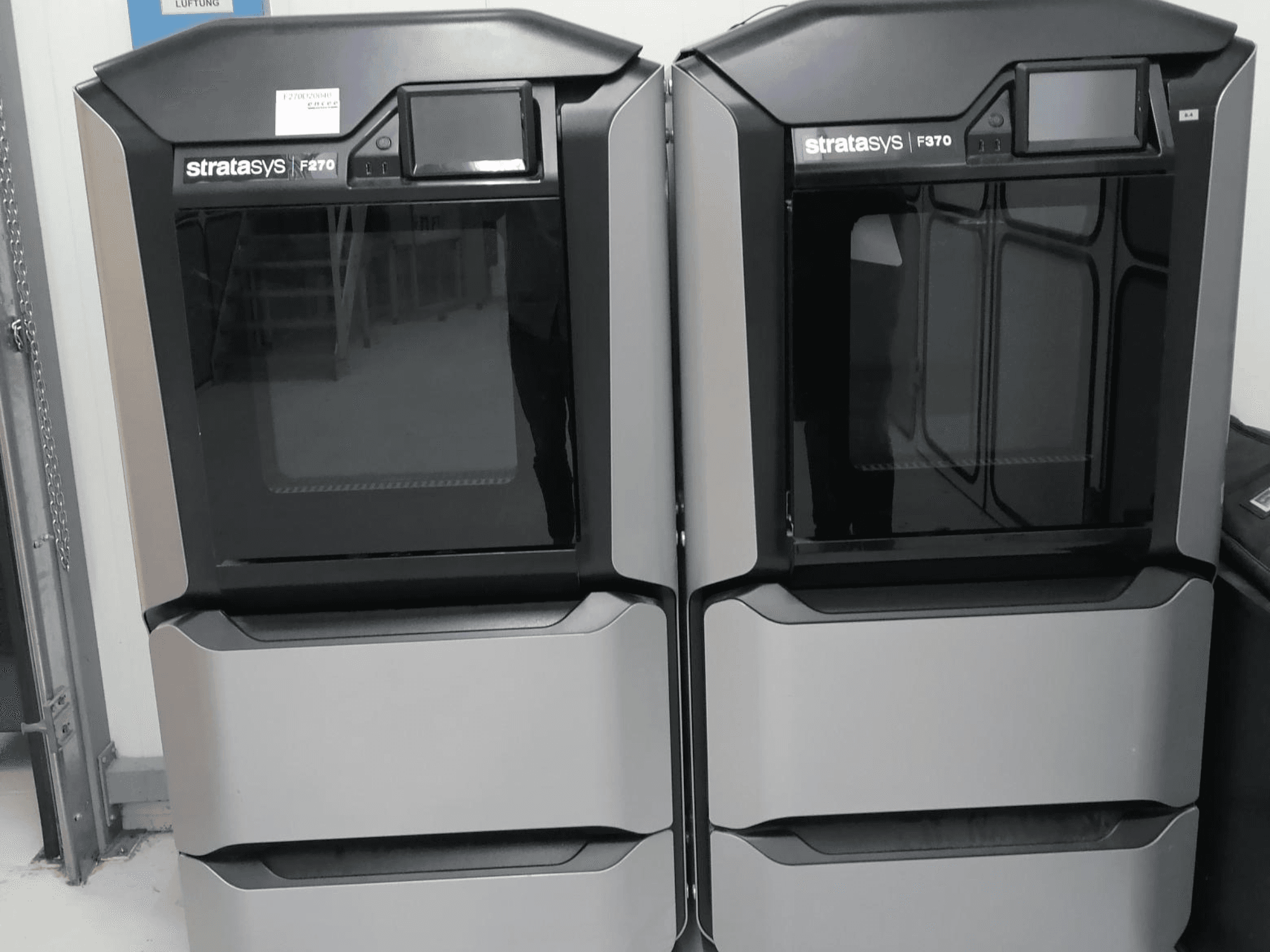 Stratasys F370 çift plastik 3D yazıcılar, kontrol ekranları ile şık siyah ve gümüş tasarıma sahip önden görünümde görüntülenir.