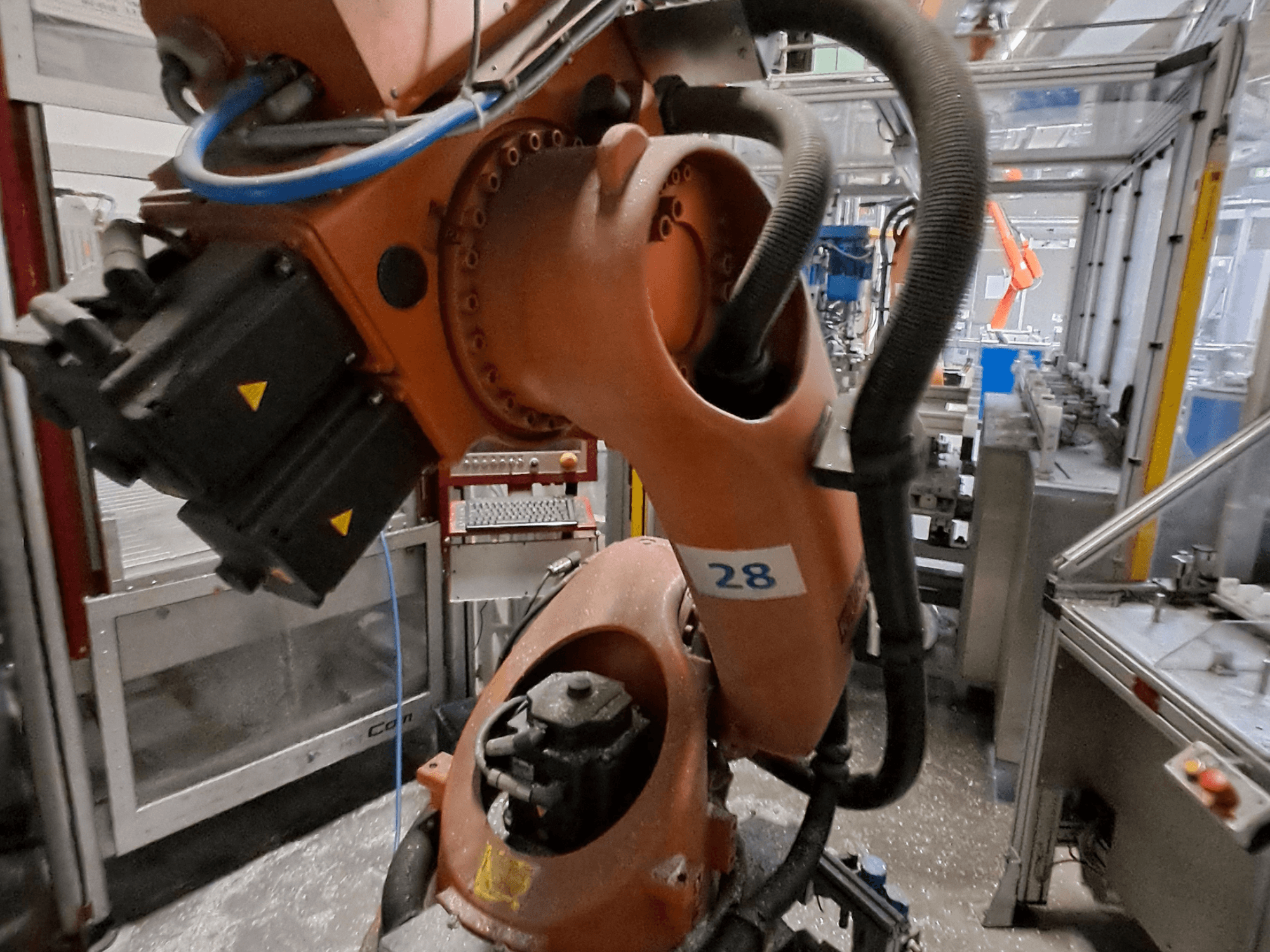 KUKA KR30-3 robot kolunun yakın çekim görüntüsü; turuncu gövdeli, 28 numaralı etiketli ve yan taraftan bakıldığında motorları ve kablolaması görülebilen.