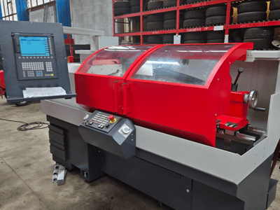 Kontrol panelli kırmızı CNC torna makinesi, önden görünüm; şeffaf kapak, takım tutucu ve saklama çekmecelerine sahiptir.