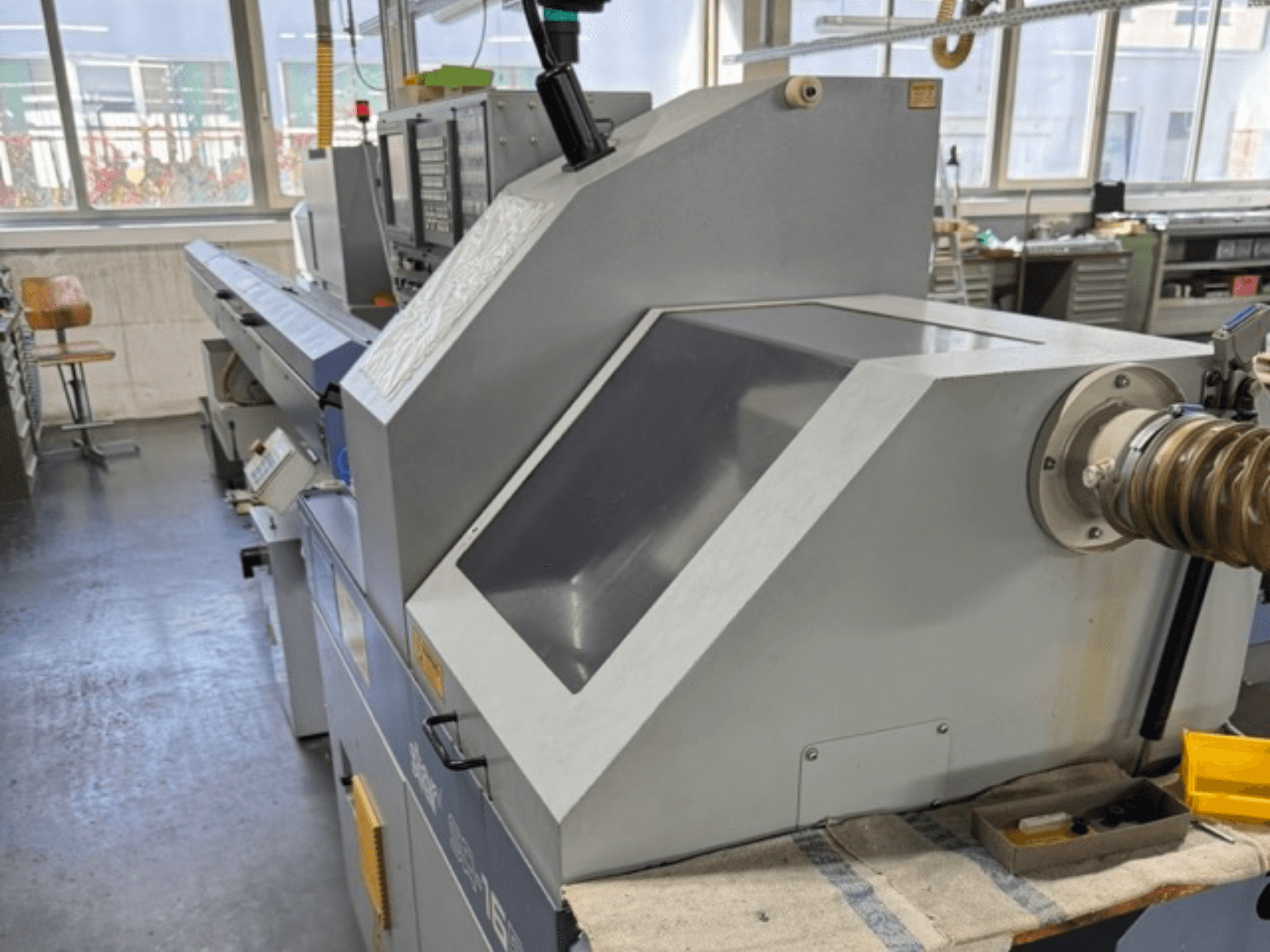 Yandan bakıldığında gri endüstriyel makinede geniş açılı bir panel, kontrol düğmeleri ve bir hortum bağlantısı bulunur.