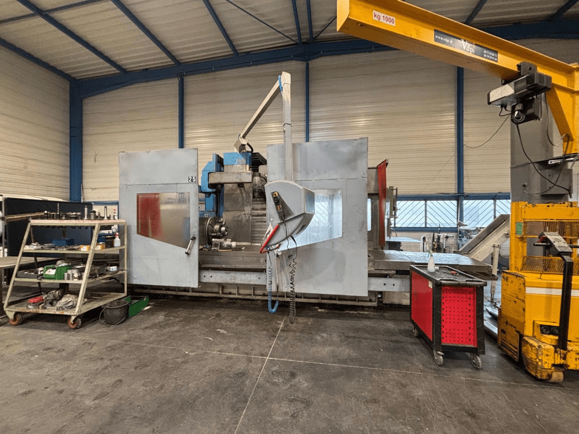 Bir atölyede yandan görünümlü CNC freze makinesi; görünür aletler ve depolama rafları. Marka ve model belirtilmemiş.