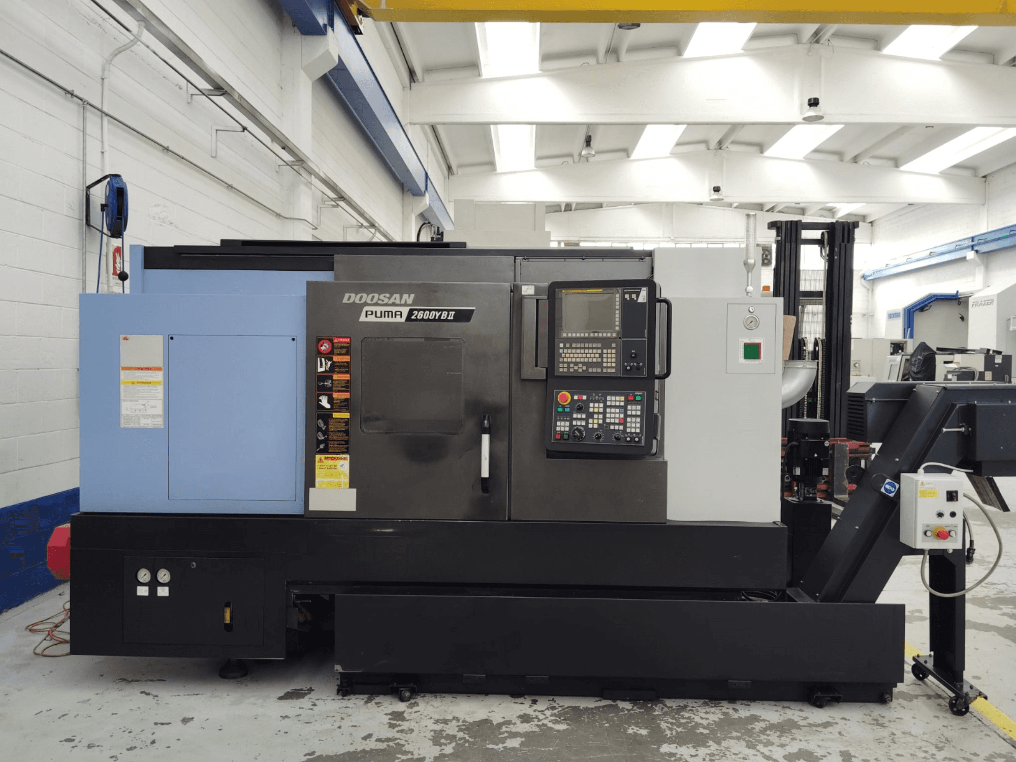 DOOSAN Puma 2600YB II yatay torna makinesinin kontrol paneli ve güvenlik etiketleri görünür şekilde önden görünümü.