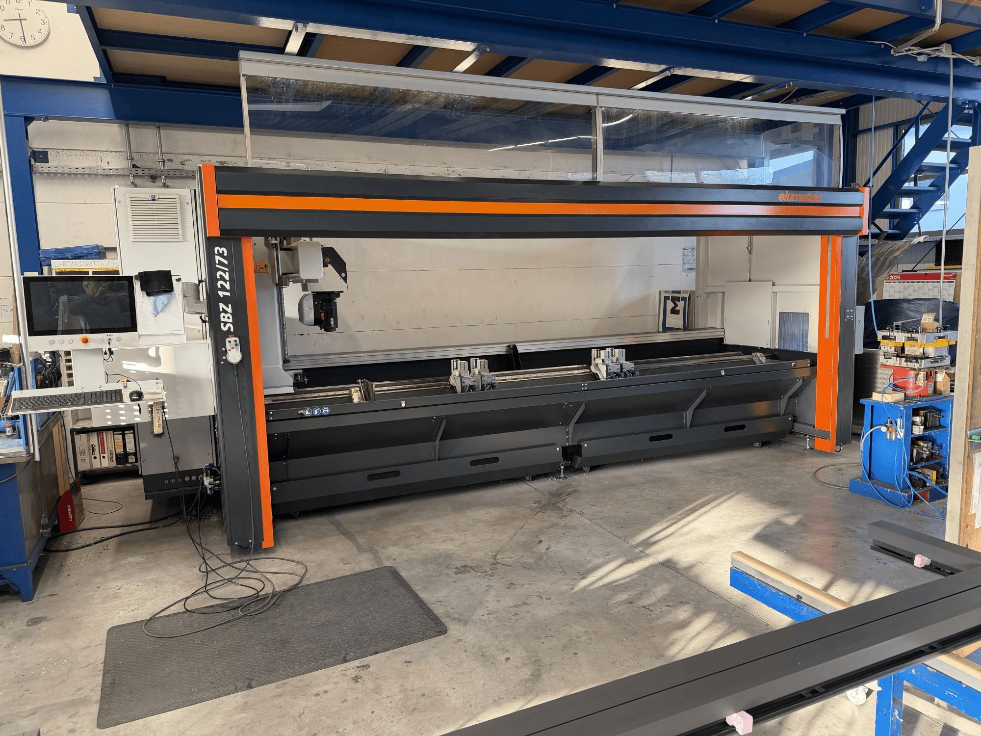 Elumatec SBZ 122/73 takım tezgahının önden görünümü, kontrol panelini, kesim alanını ve çalışma alanı düzenini gösterir.