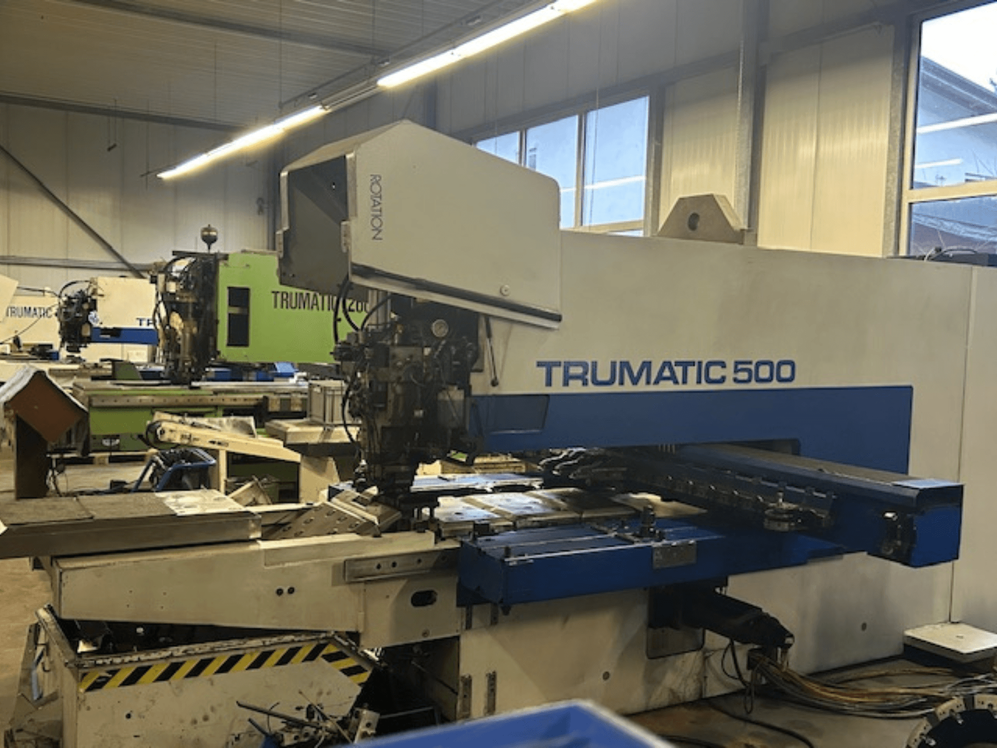 TRUMPF TRUMATIC 500 CNC delme makinesi, önden görünüm, kontrol paneli ve mekanik parçalar. Endüstriyel atölye ortamı.
