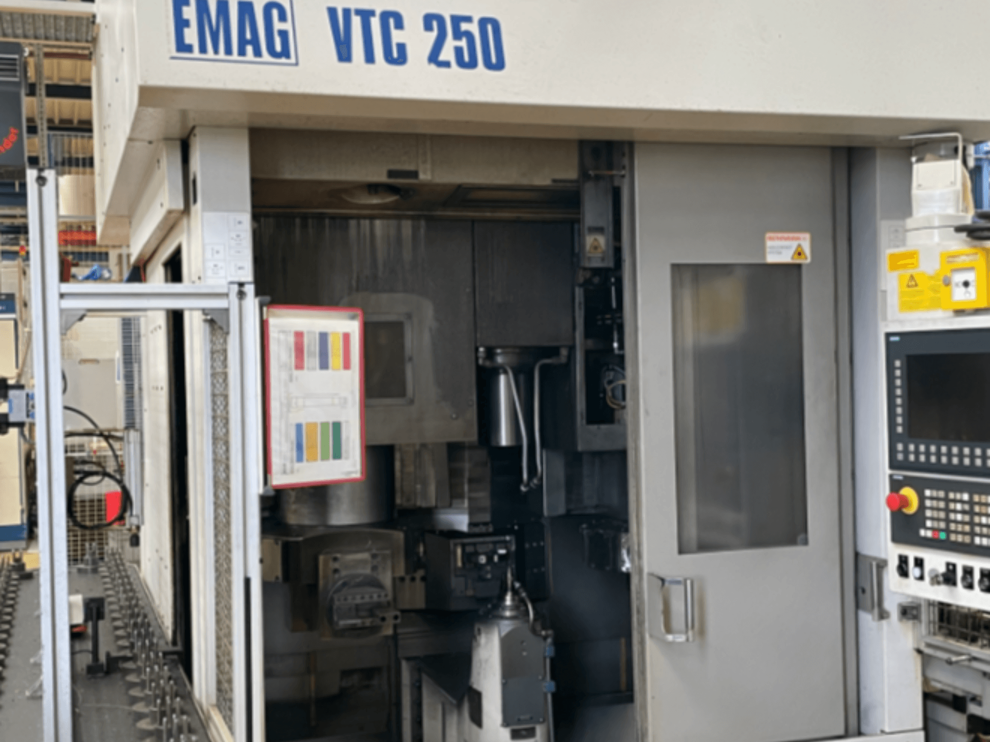 EMAG VTC 250 dikey torna tezgahının önden görünümü; kontrol paneli, kullanım arayüzü ve açık erişim kapısı görülmektedir.