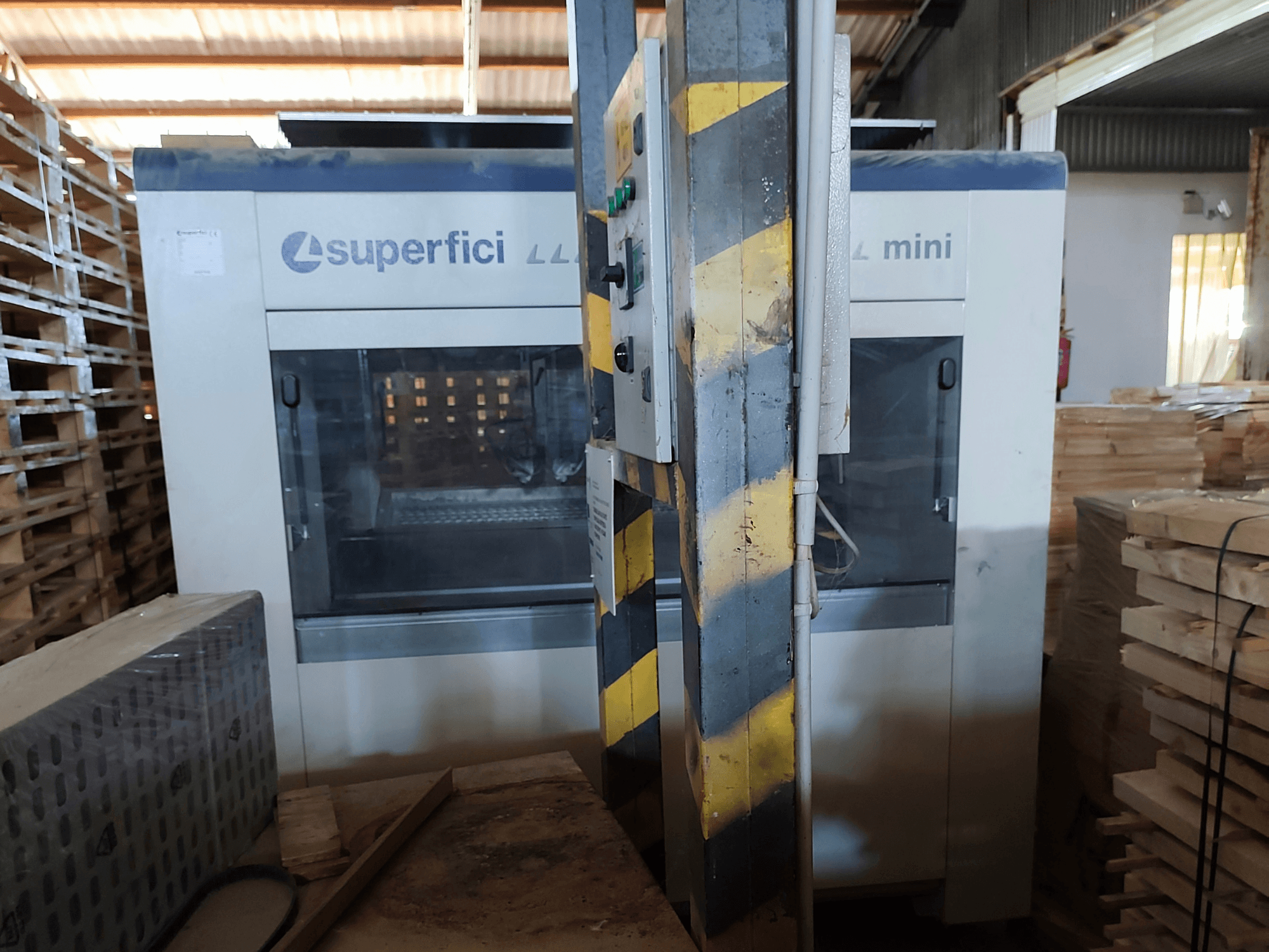 SCM Superfici Mini ahşap işleme makinesinin önden görünümü; kontrol paneli ve çevresindeki ahşap paletler görülmektedir.