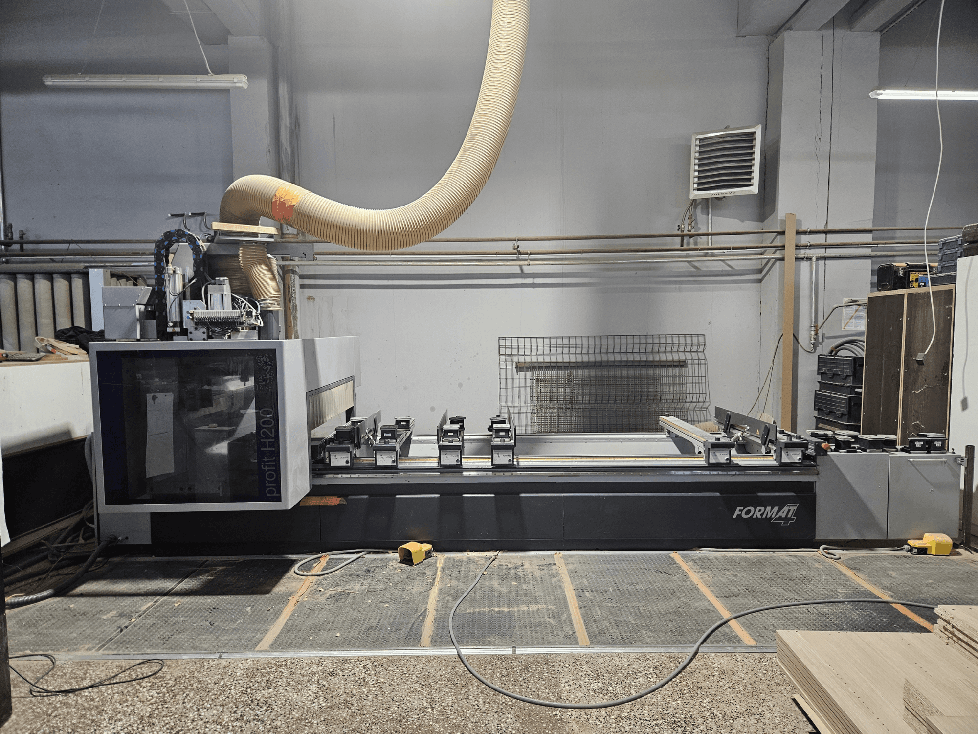 Bir atölyede FORMAT profit H200 CNC makinesi, yandan görünüm, çalışma yüzeyini ve toz emme sistemini gösterir.