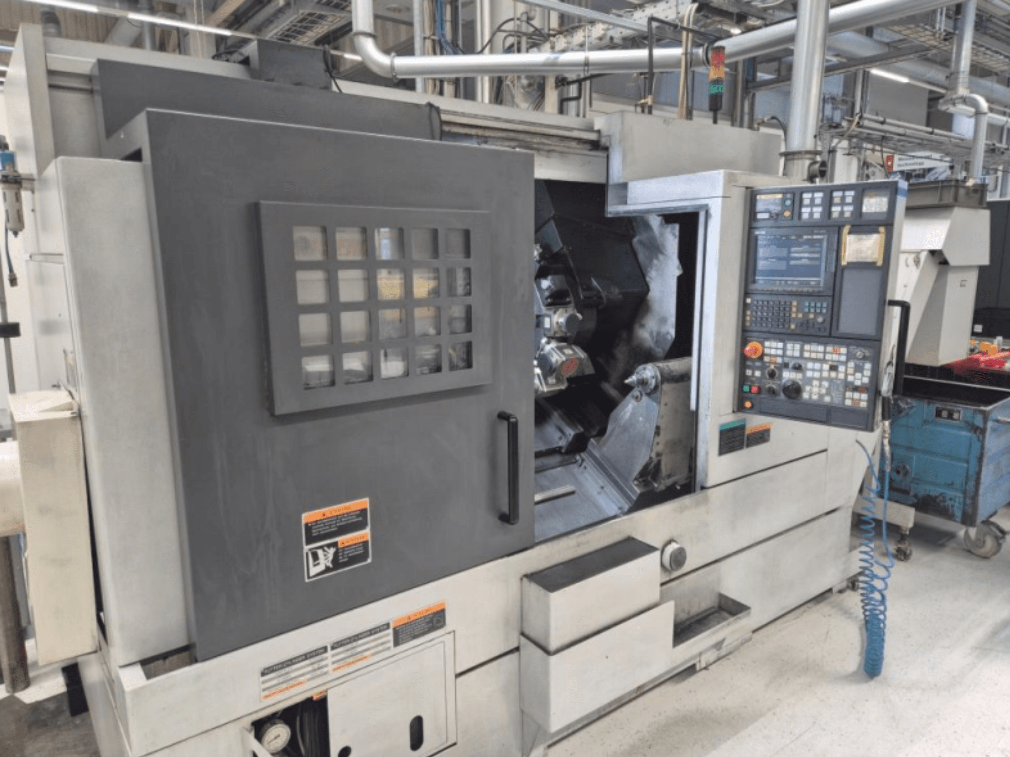 Kontrol panelli CNC torna makinesi, önden görünüm. Görünür bir çalışma alanına ve güvenlik penceresine sahiptir, markası bilinmiyor.