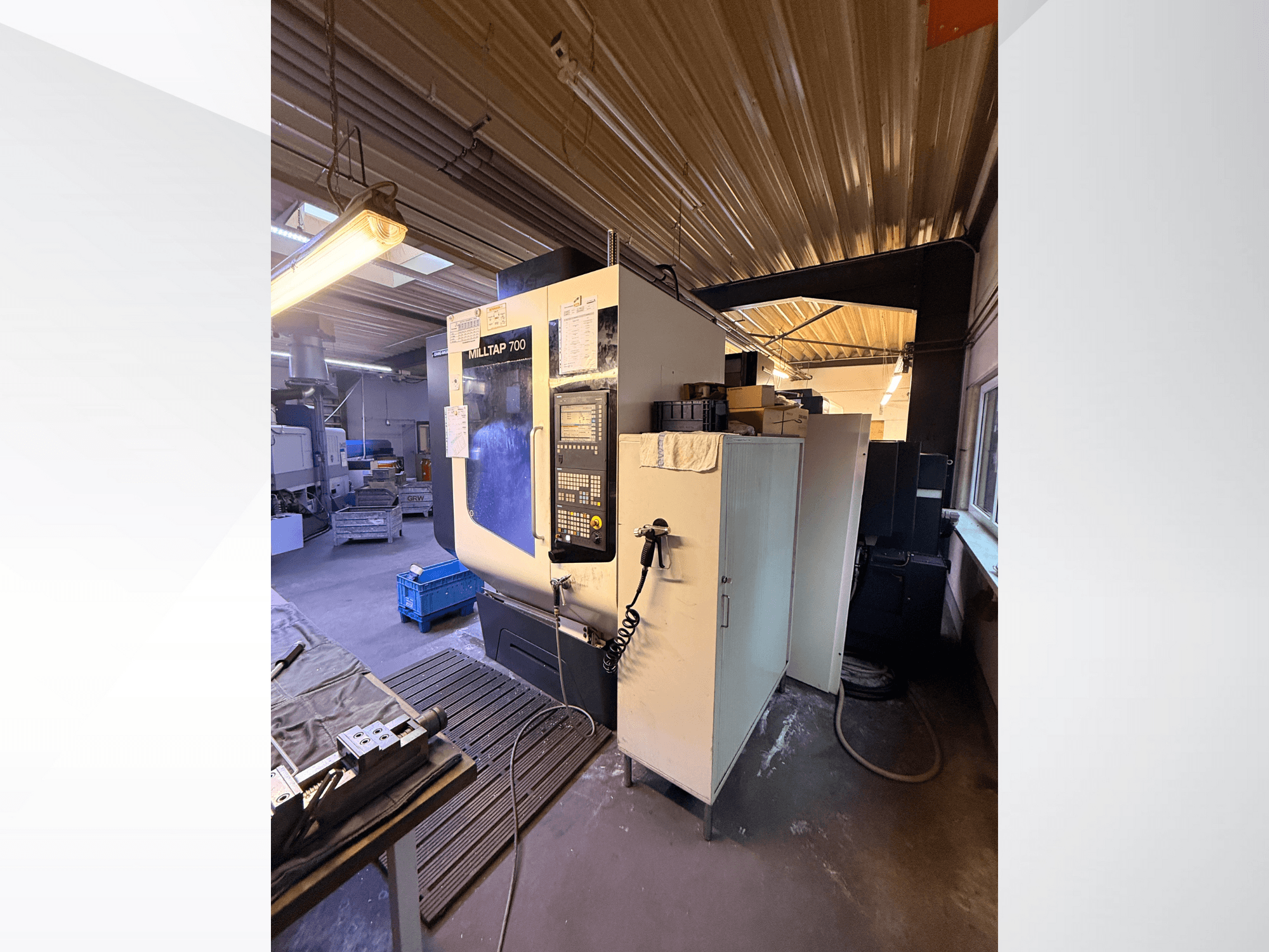 Atölyede Milltap 700 CNC makinesi; önden görünüm kontrol panelini, takım raflarını ve üzerinde aydınlatma bulunan depolama alanlarını göstermektedir.