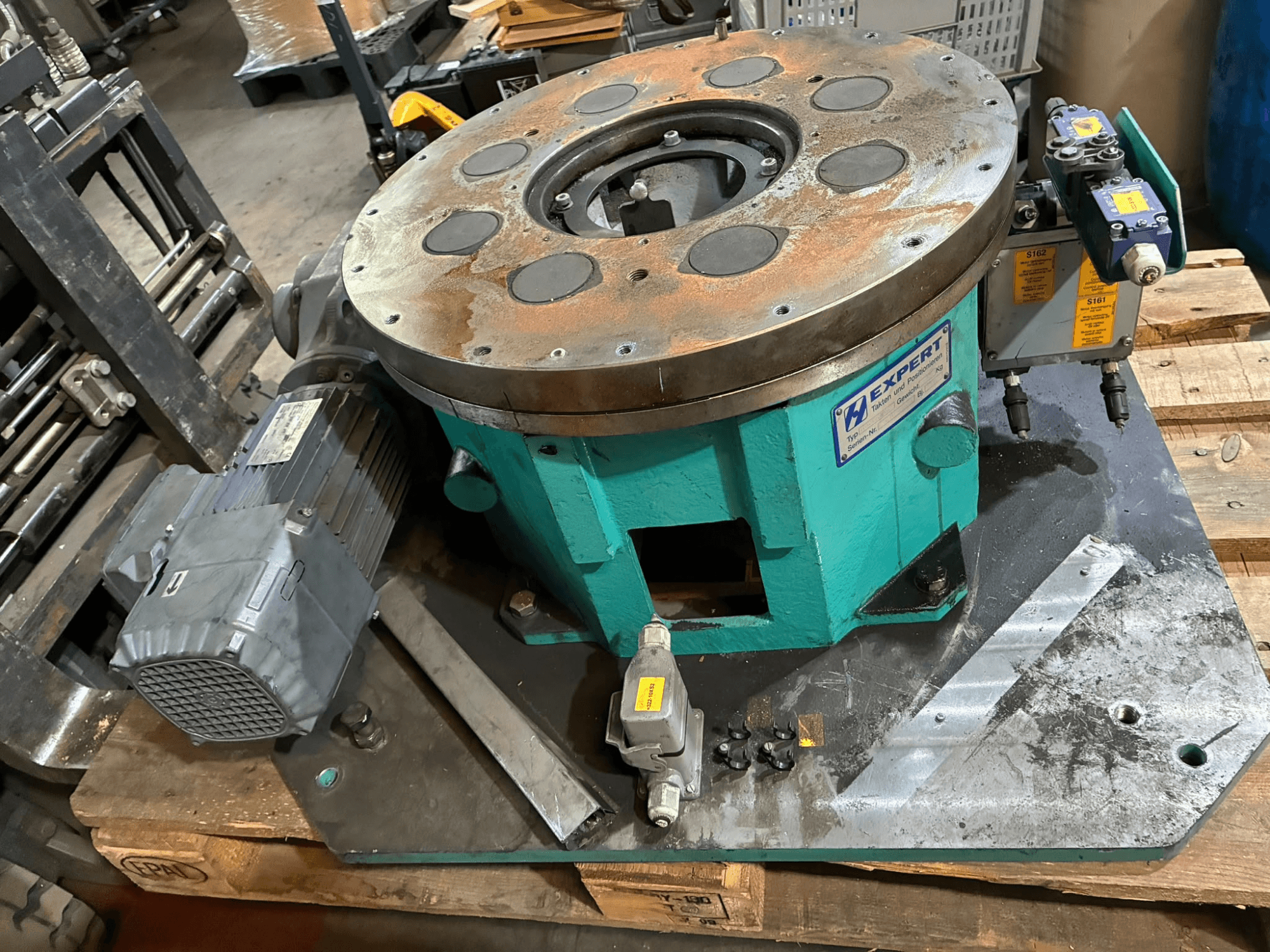 EDX810/0250/8 Otomasyon Ekipmanı, önden görünüm; bir motor, kontrol paneli ve üzerinde çok sayıda delik bulunan dairesel bir plaka içerir.