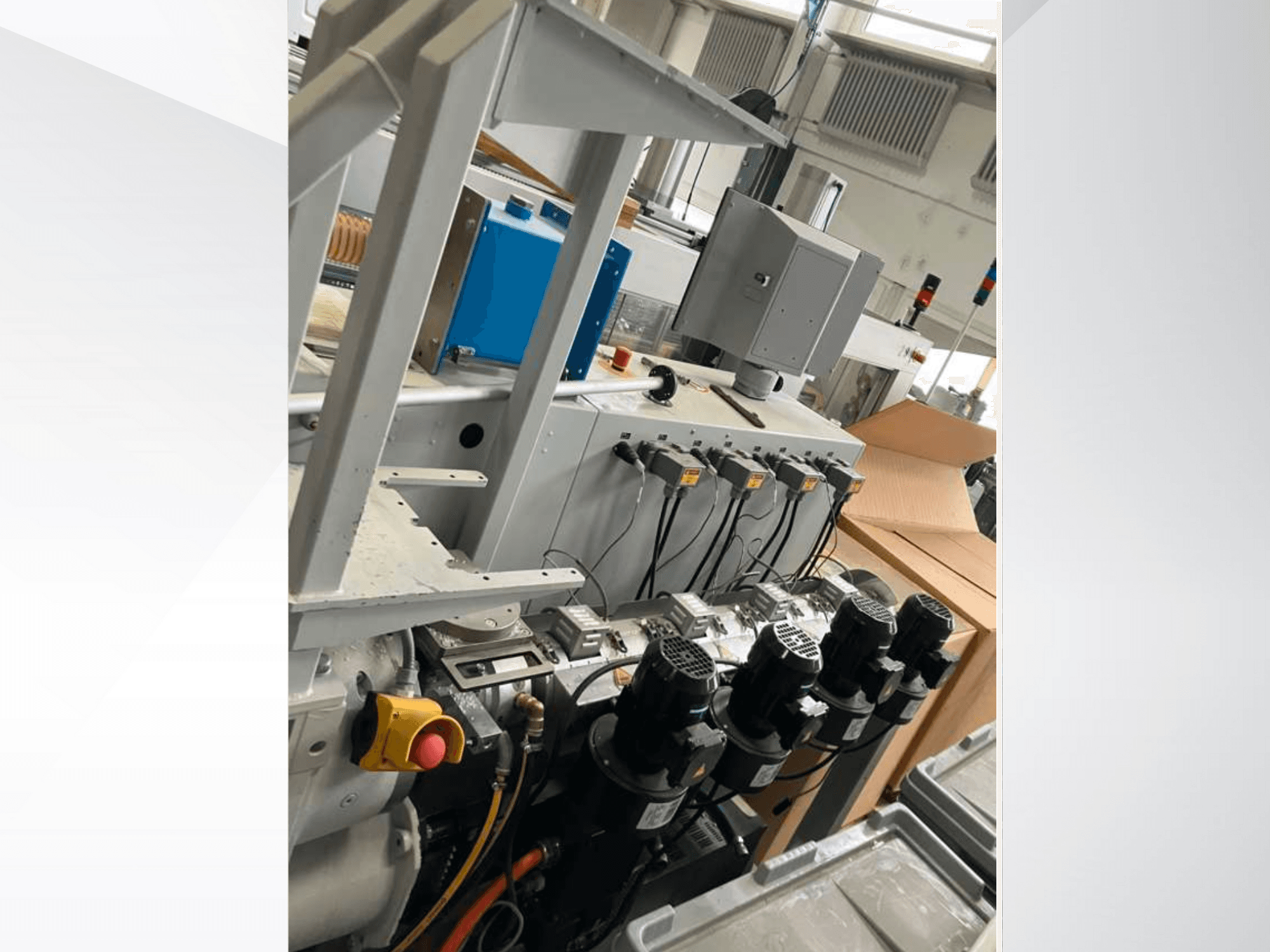 Birden fazla motor, gösterge ve bir monitör içeren endüstriyel makine kontrol paneli; fabrika ortamında yandan görünüm.