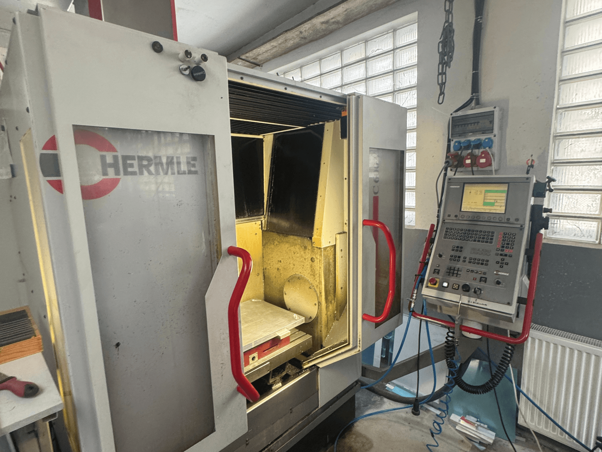 HERMLE C600V dikey işleme merkezi, açık kapı, kontrol paneli ve iç çalışma alanını gösteren önden görünüm.
