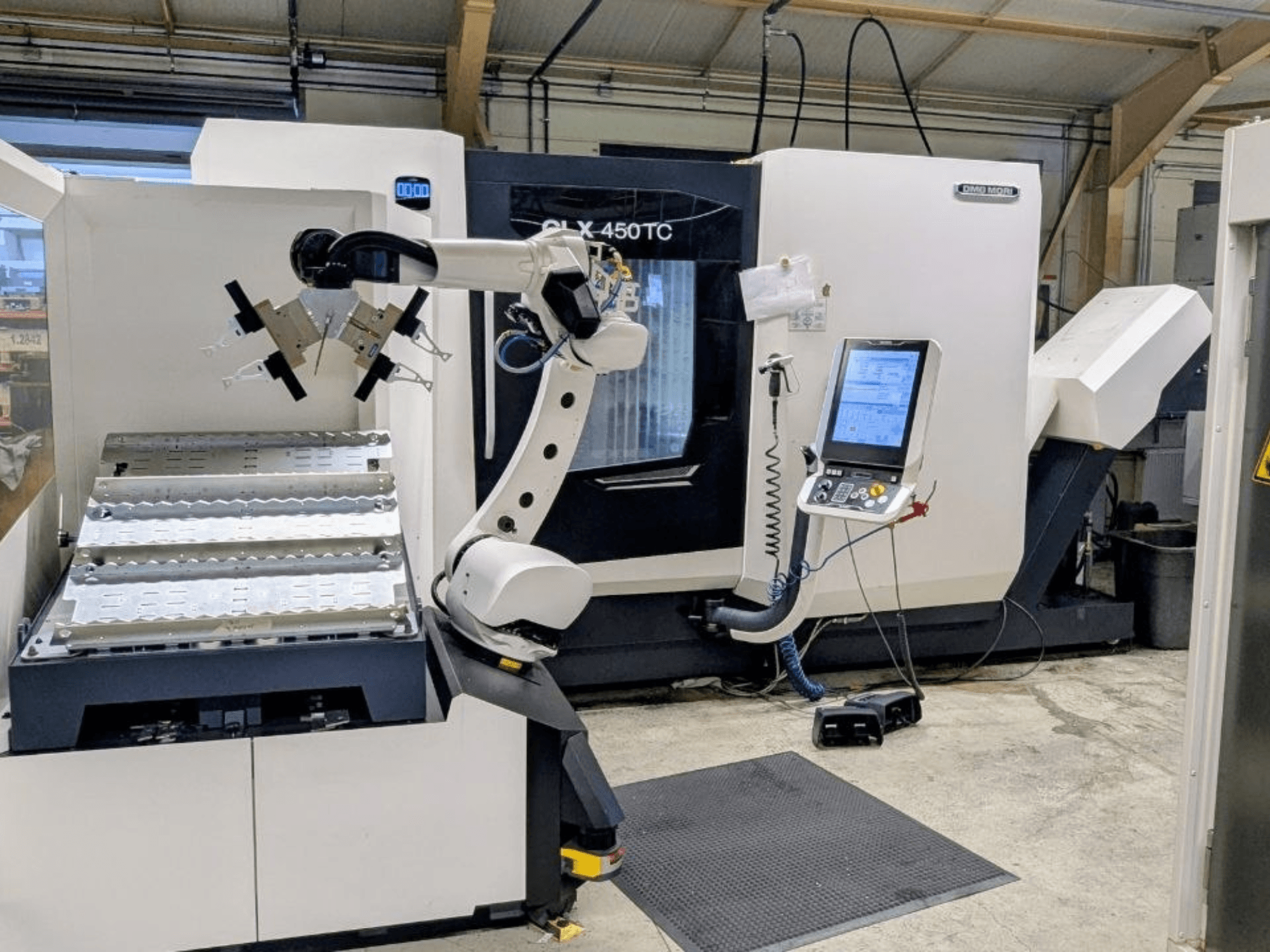 Robo2go donanımlı DMG MORI CLX 450 TC, önden görünüm; makinenin yanındaki robot kolu ve kontrol paneli gösterilmektedir.