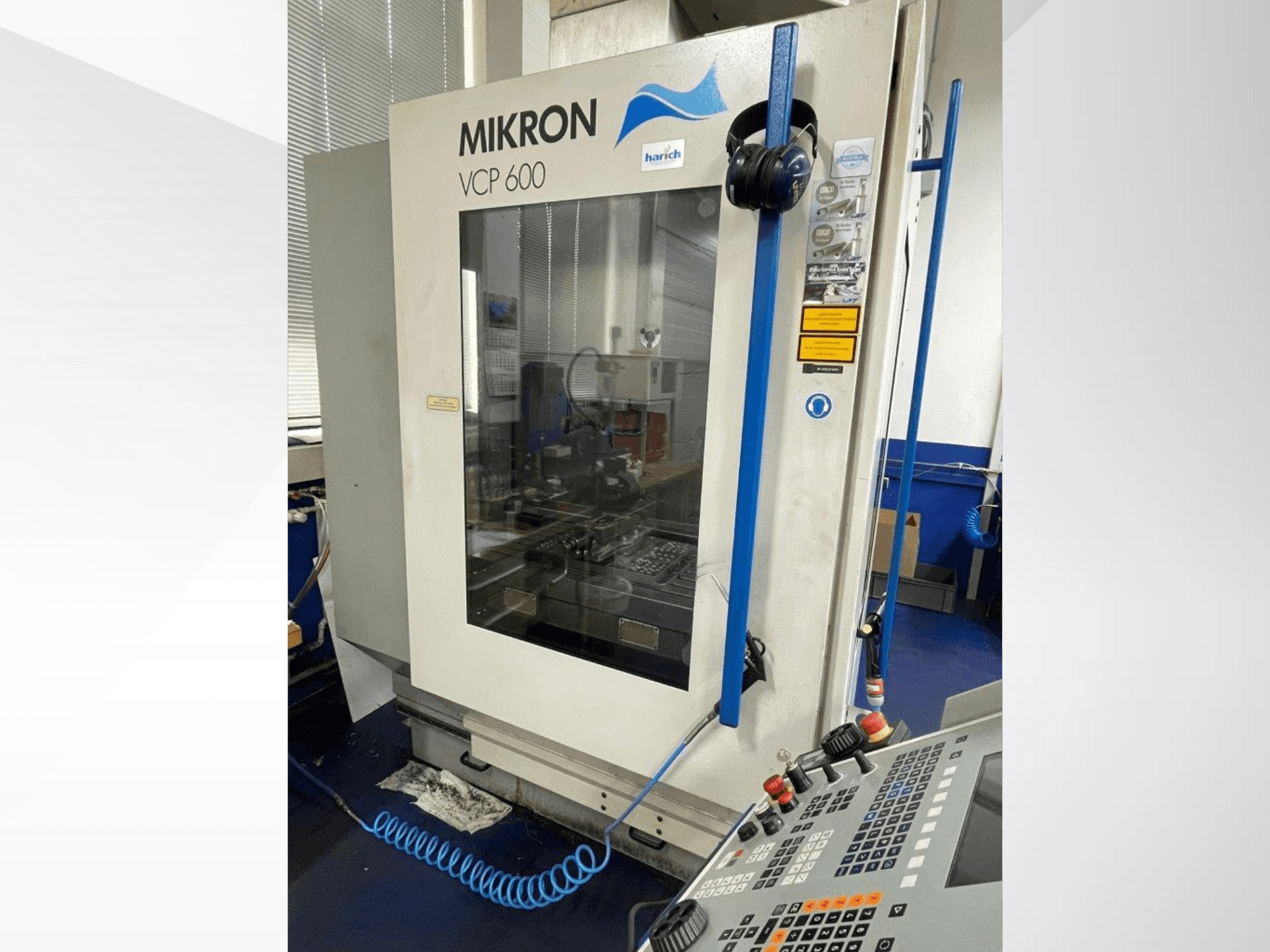 Mikron VCP 600 CNC makinesi, önden görünüm, düğmeli kontrol paneli ve camın arkasında görünür işleme alanı.